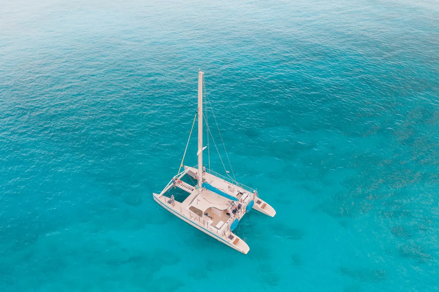 Aerial view of a catamaran sailing in clear turquoise water