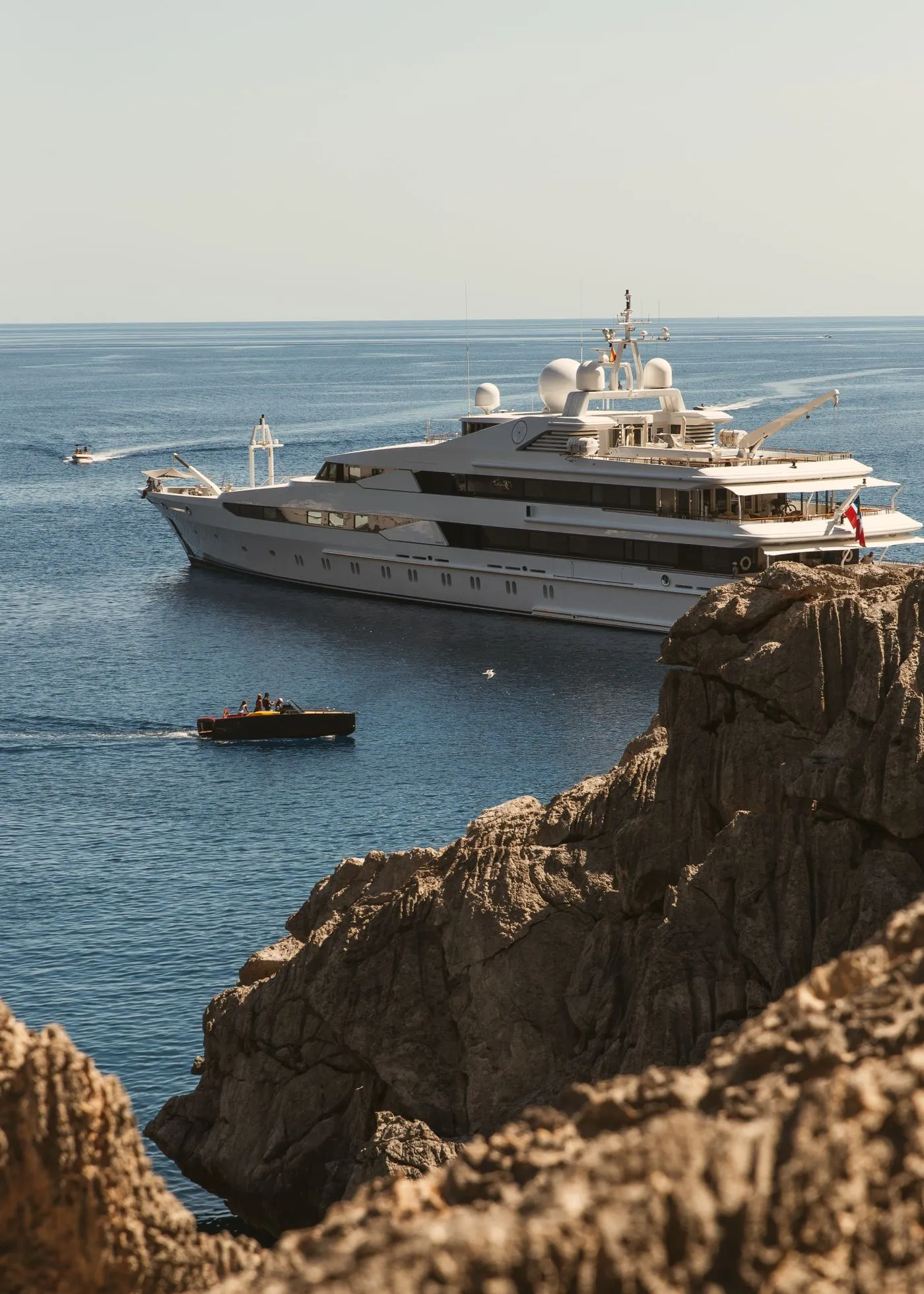 Luxury motor yacht running past rocky Mediterranean cliffs