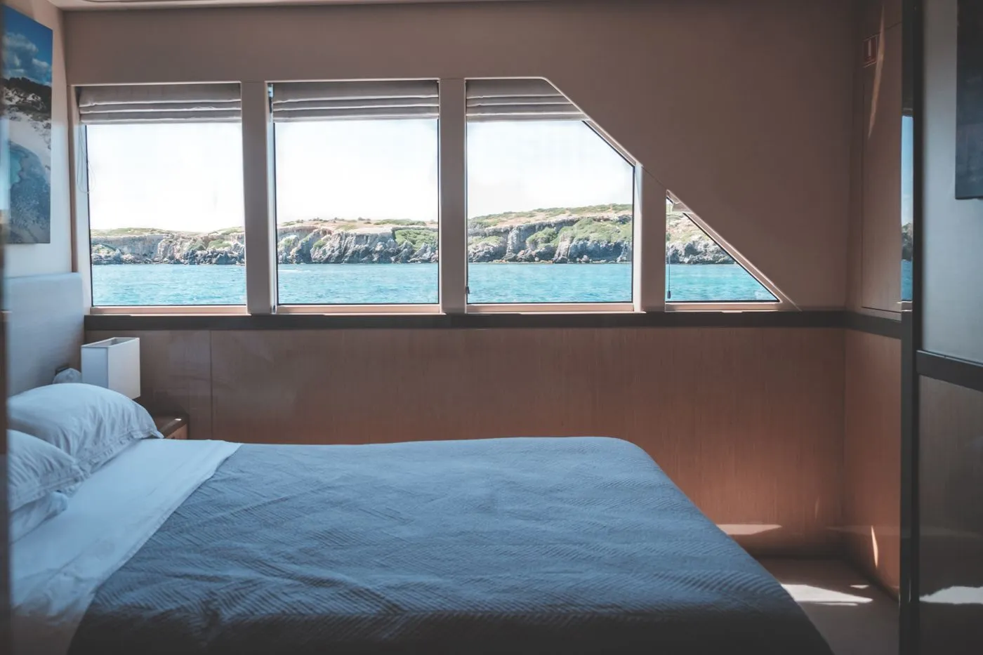 Compact yacht cabin with a made bed beneath a porthole