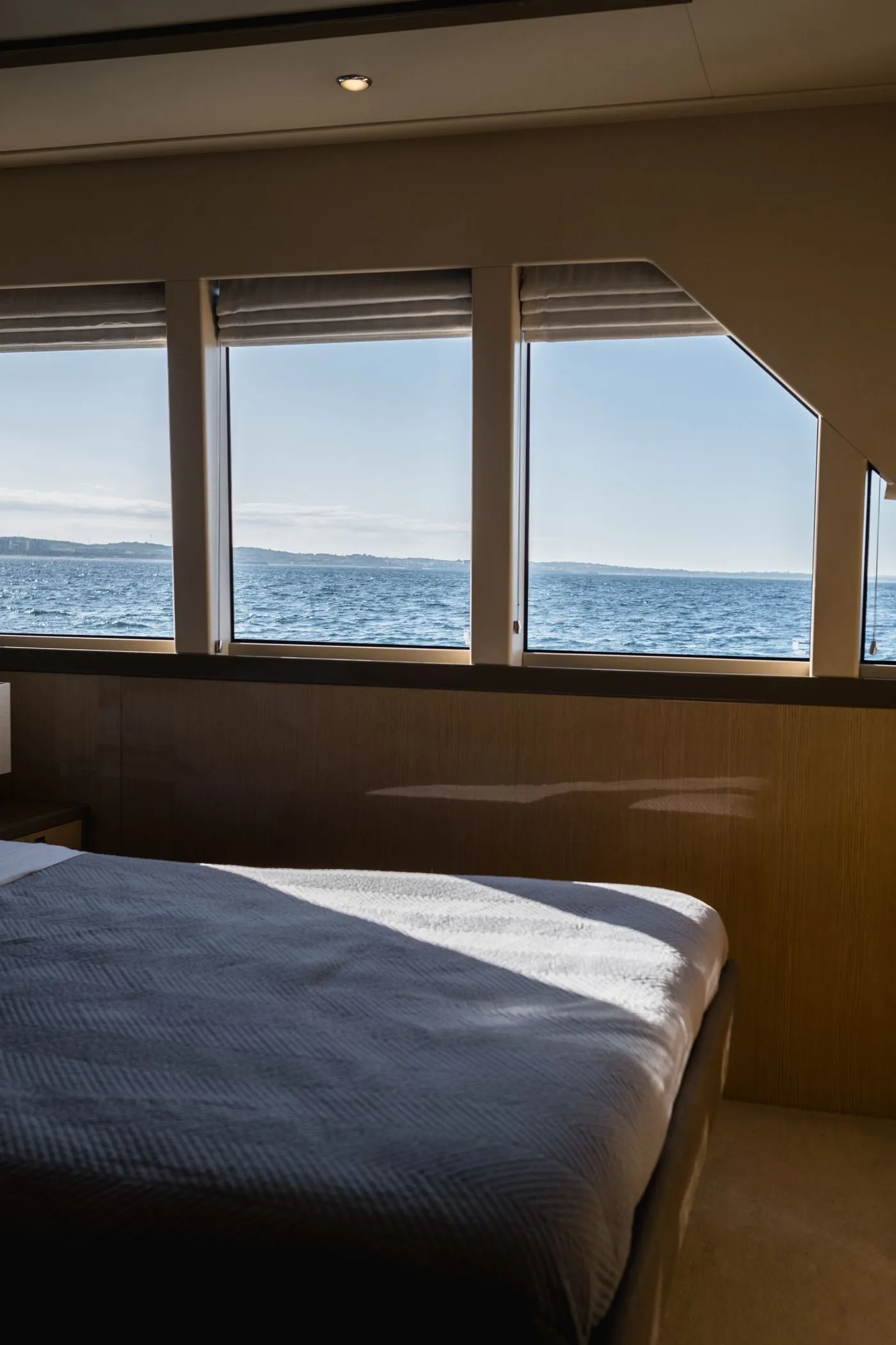 Yacht bedroom with a low bed and a wide window on to open sea