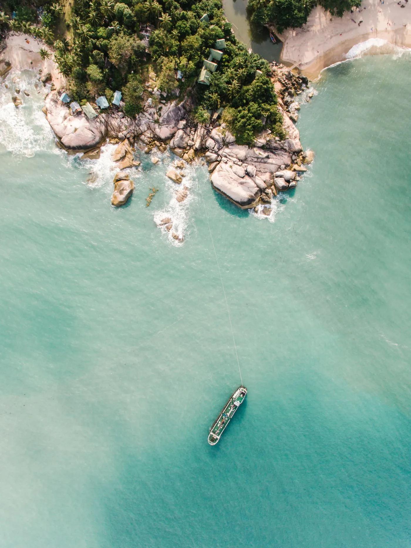 Aerial view of a lone yacht on a tropical coastline