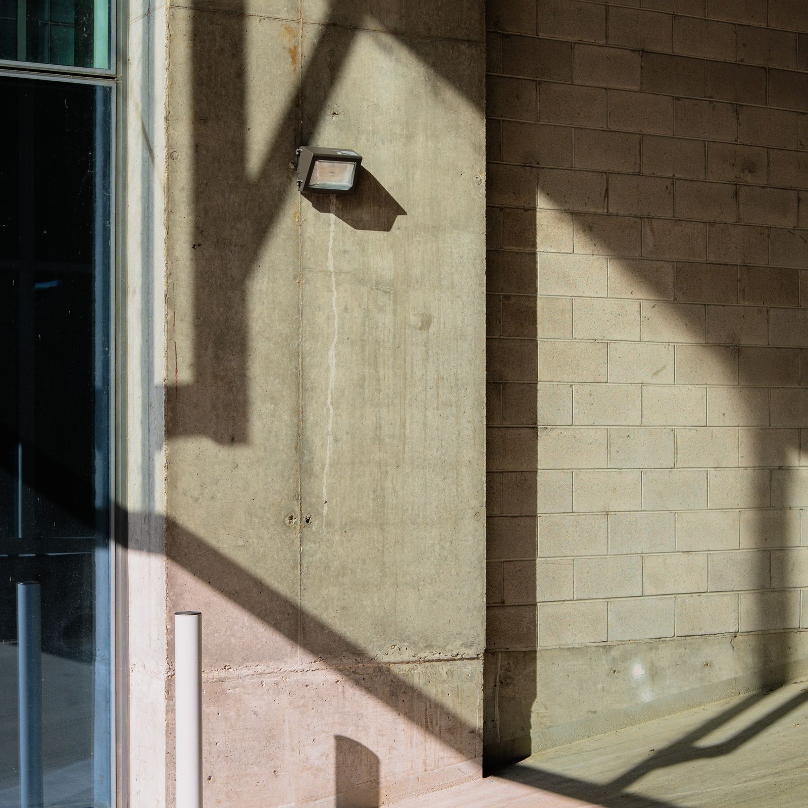 Sunlit concrete wall with a hard diagonal shadow across it