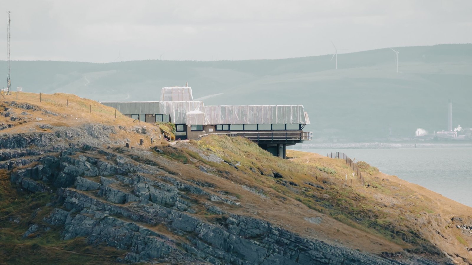Low building on a coastal cliff under heavy grey cloud