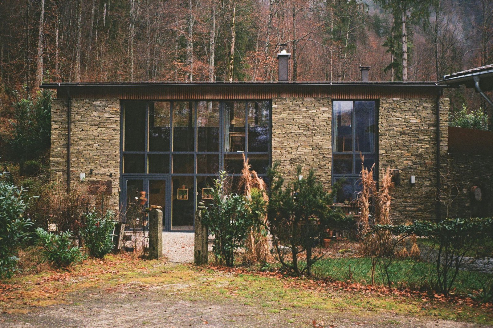 Stone and glass house standing among autumn trees