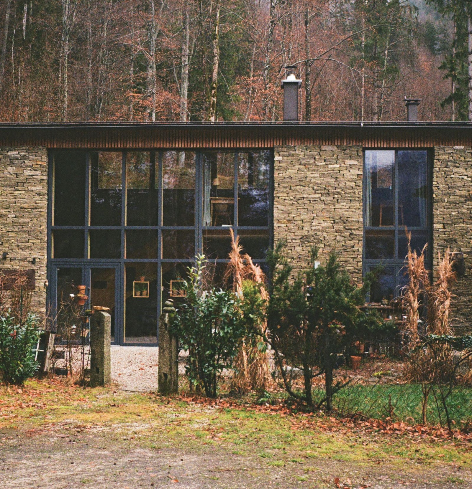 Stone and glass house standing among autumn trees