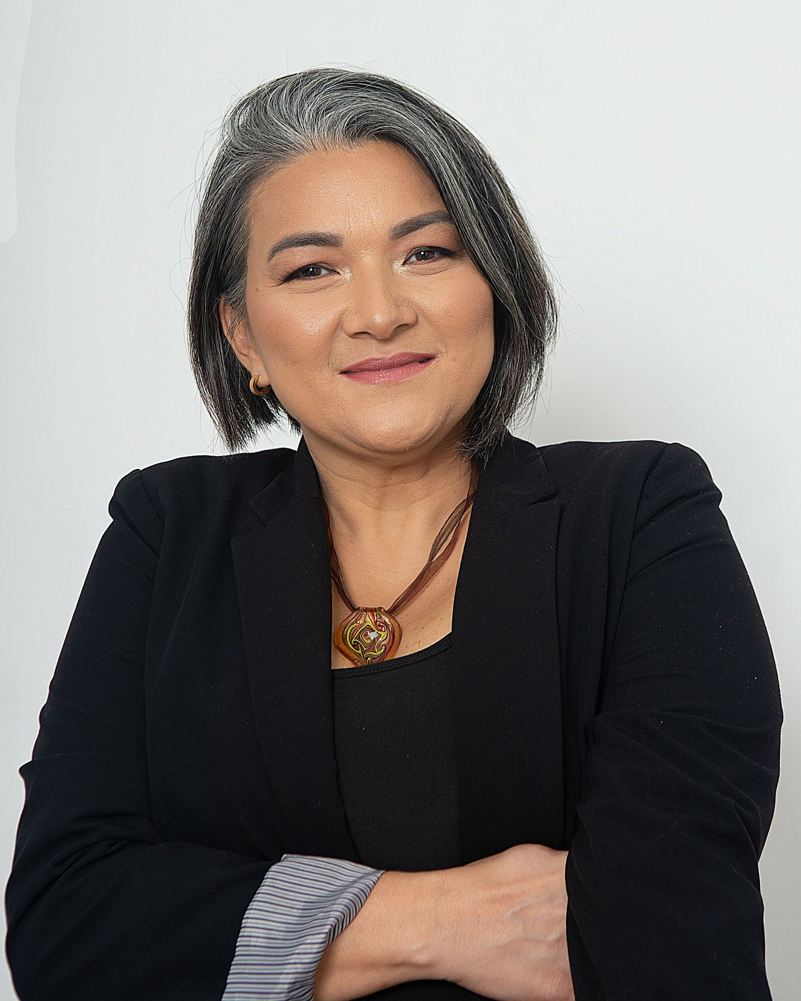 Portrait of a woman with grey hair in a dark jacket against a pale background