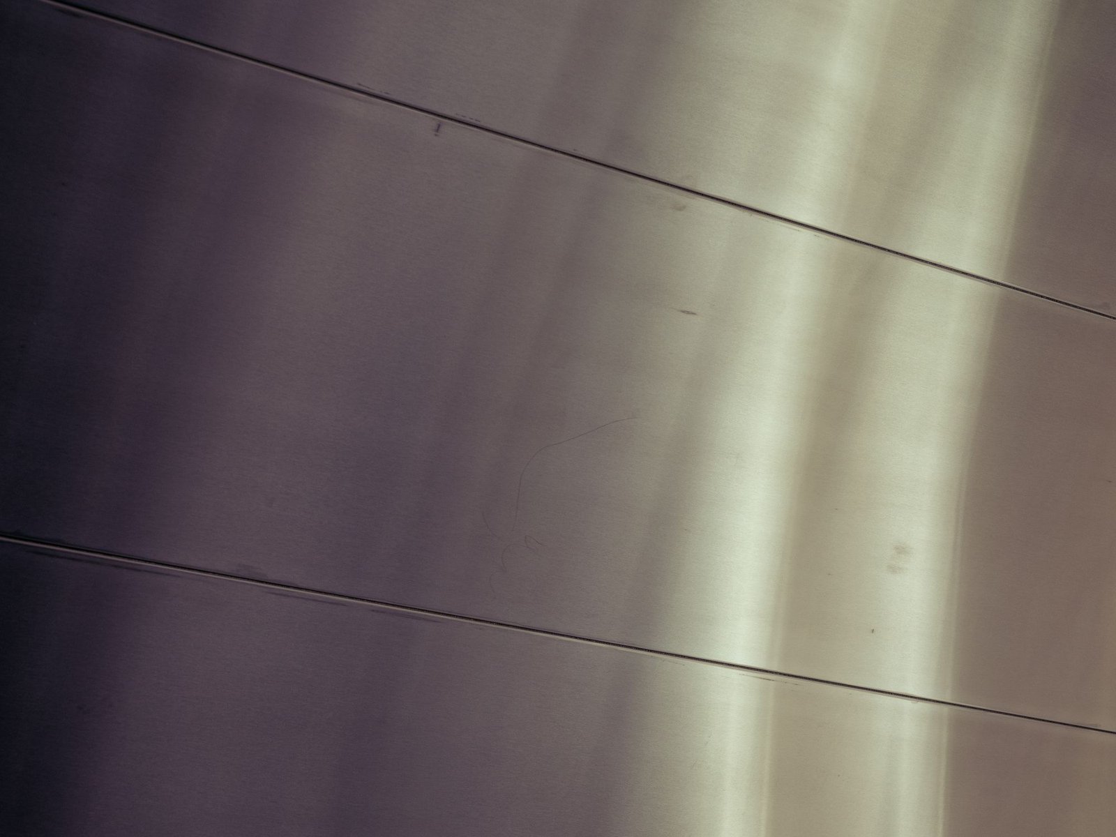 Brushed metal surface curving away under soft light