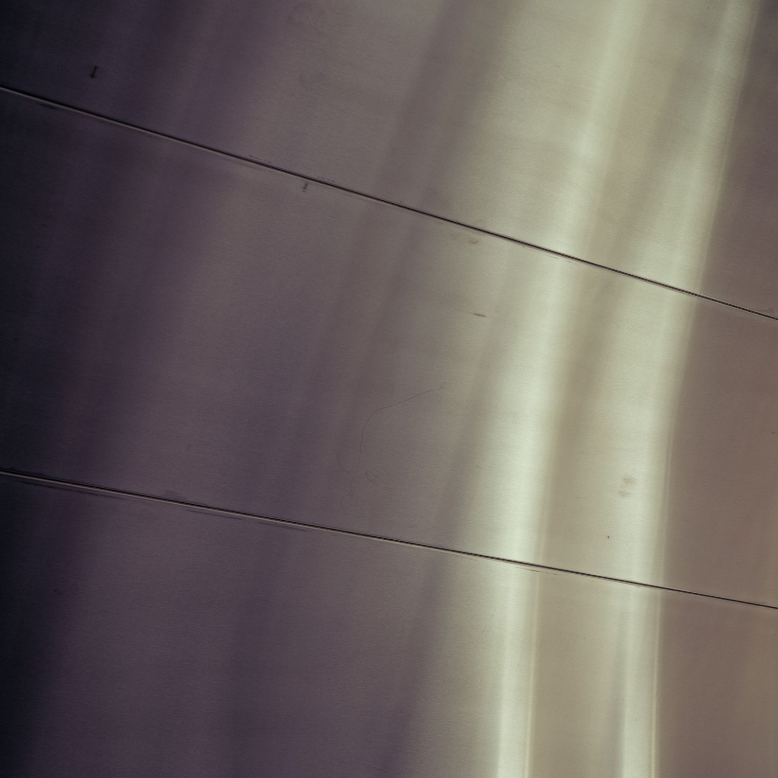 Brushed metal surface curving away under soft light