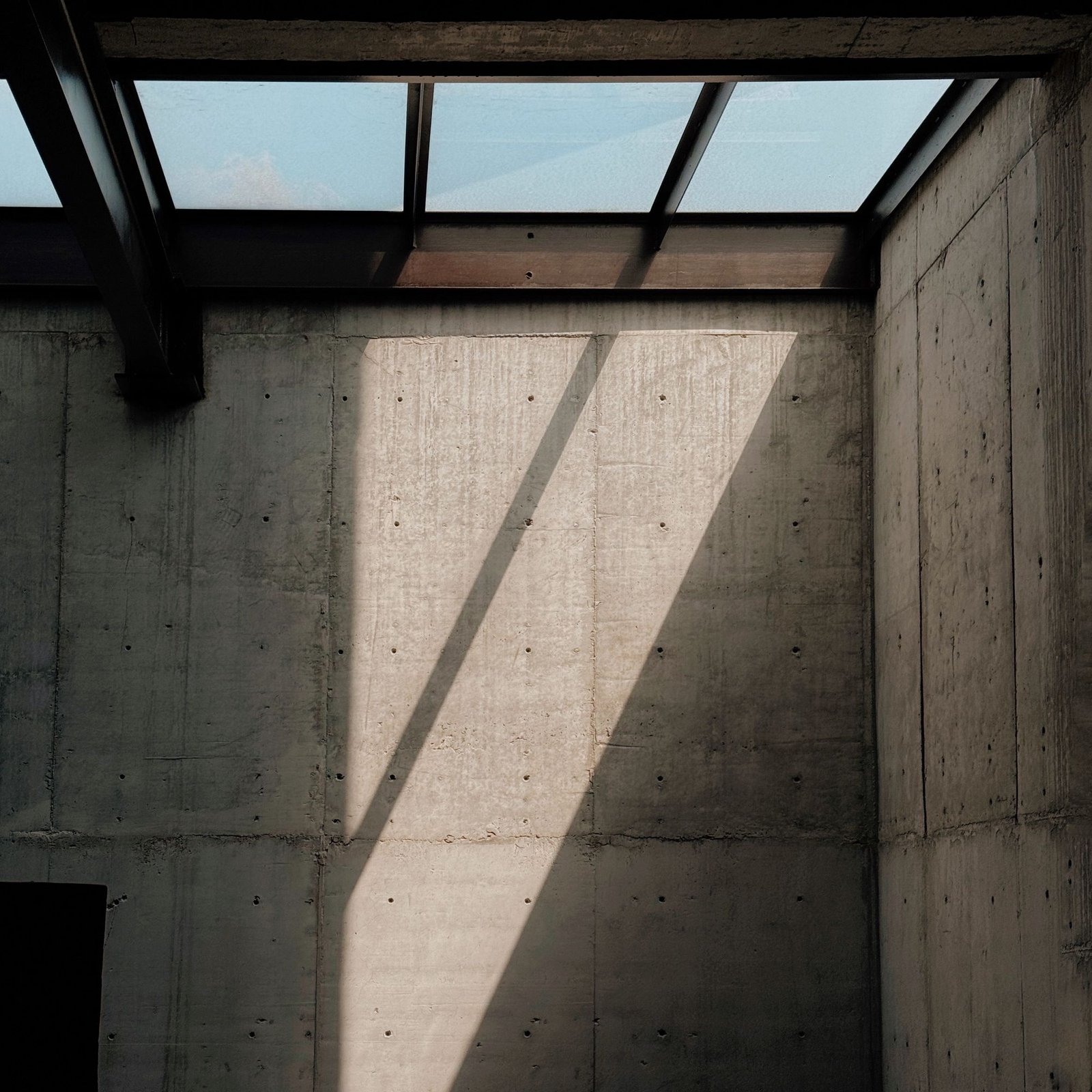 Concrete walls lit by a skylight casting a sharp geometric shadow