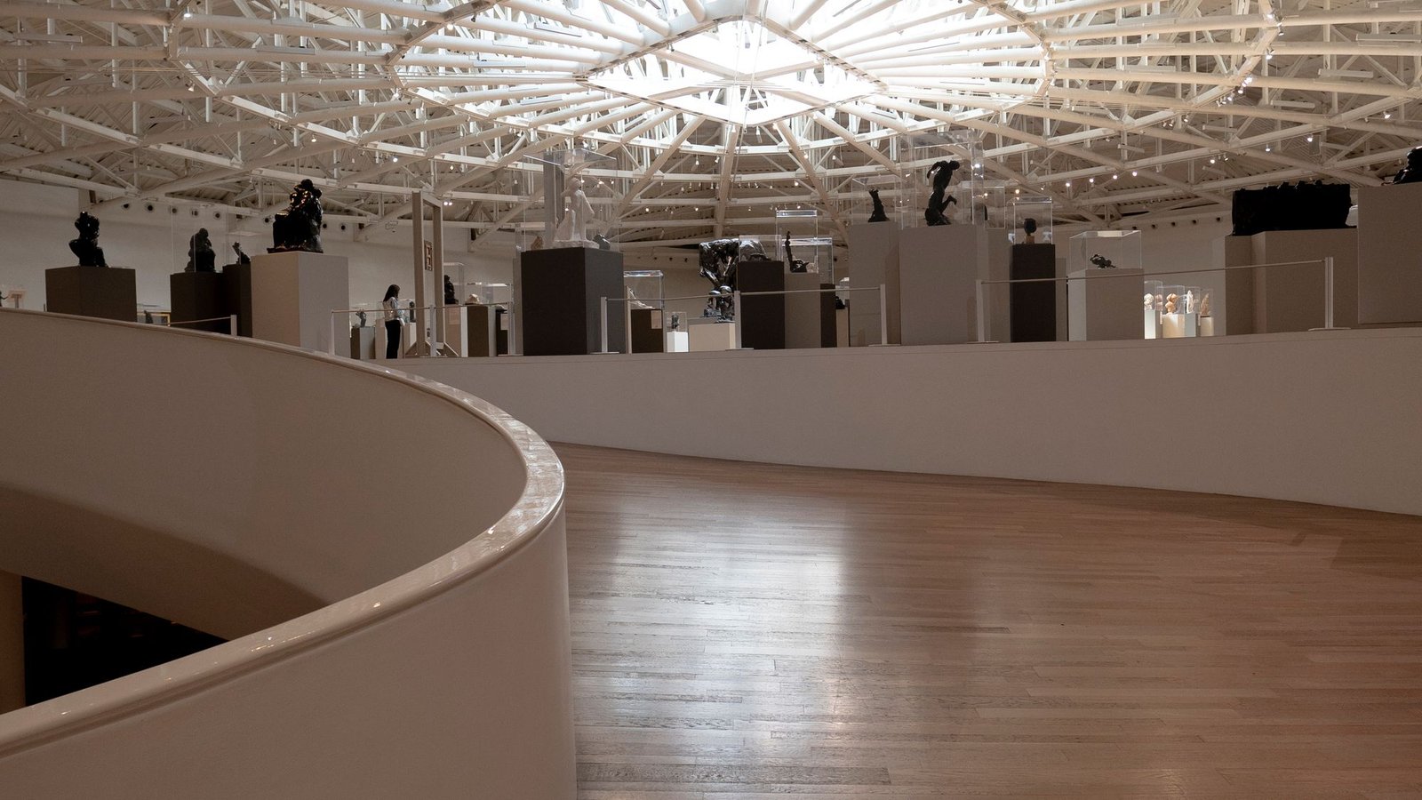 Curved white gallery interior with a polished timber floor