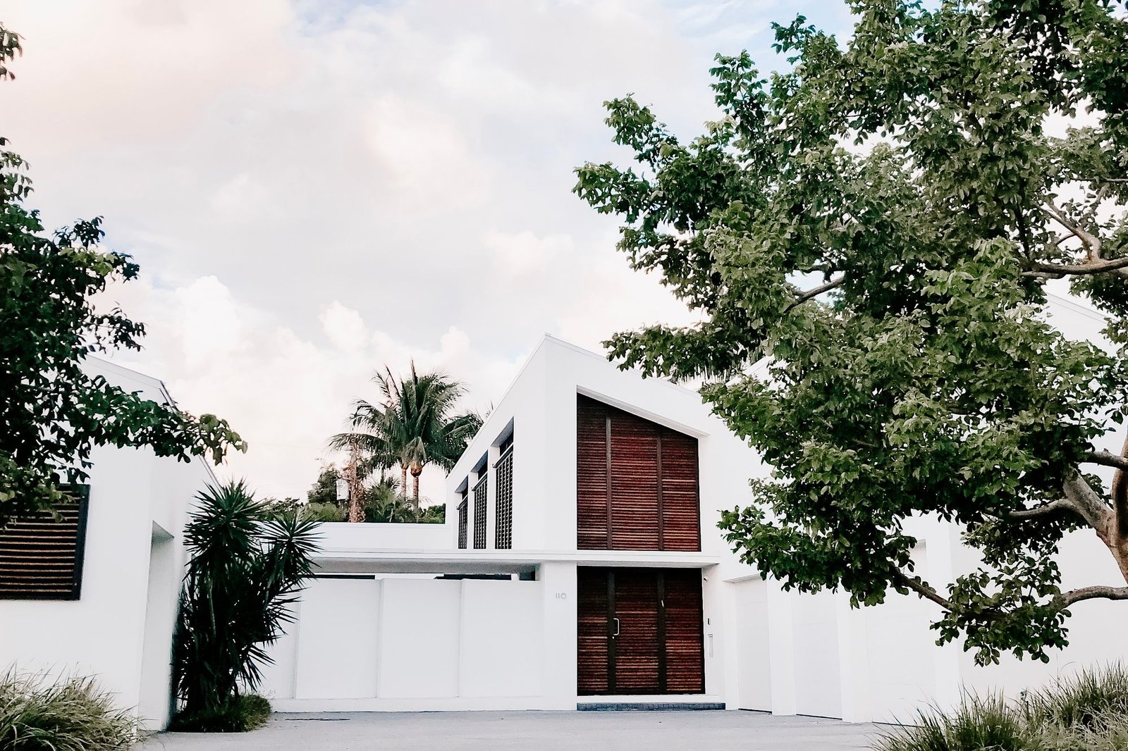 Completed minimal white house with a mature tree in a gravel forecourt