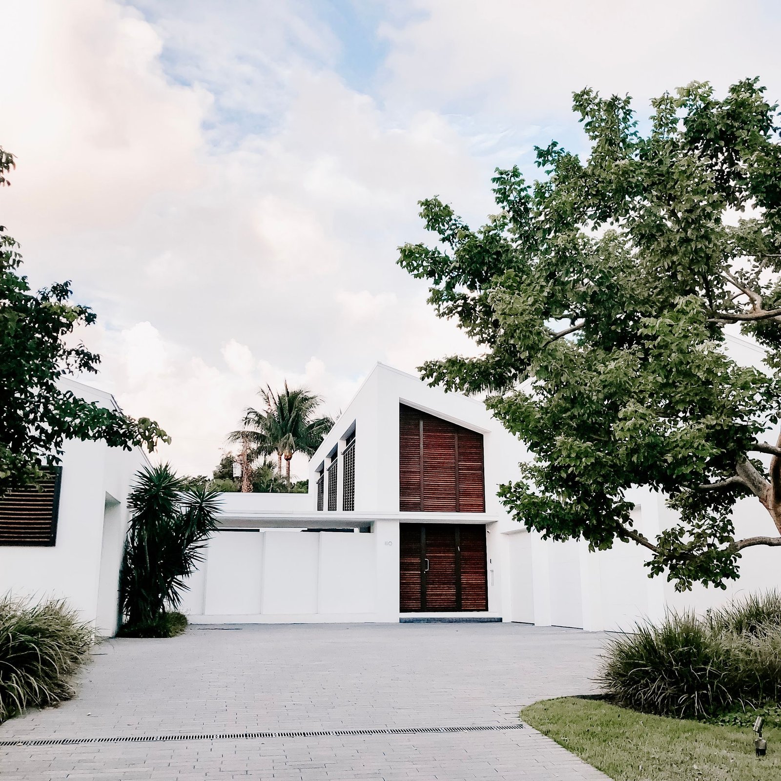 Minimal white house with a single mature tree in a gravel forecourt