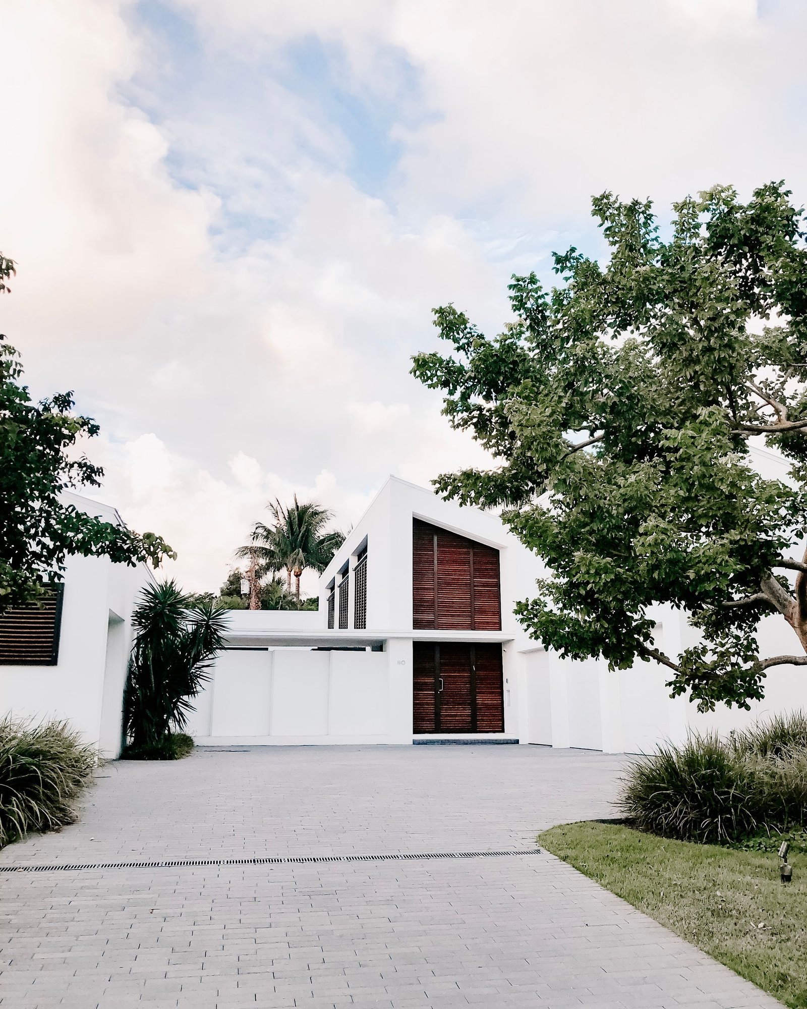 Completed minimal white house with a mature tree in a gravel forecourt