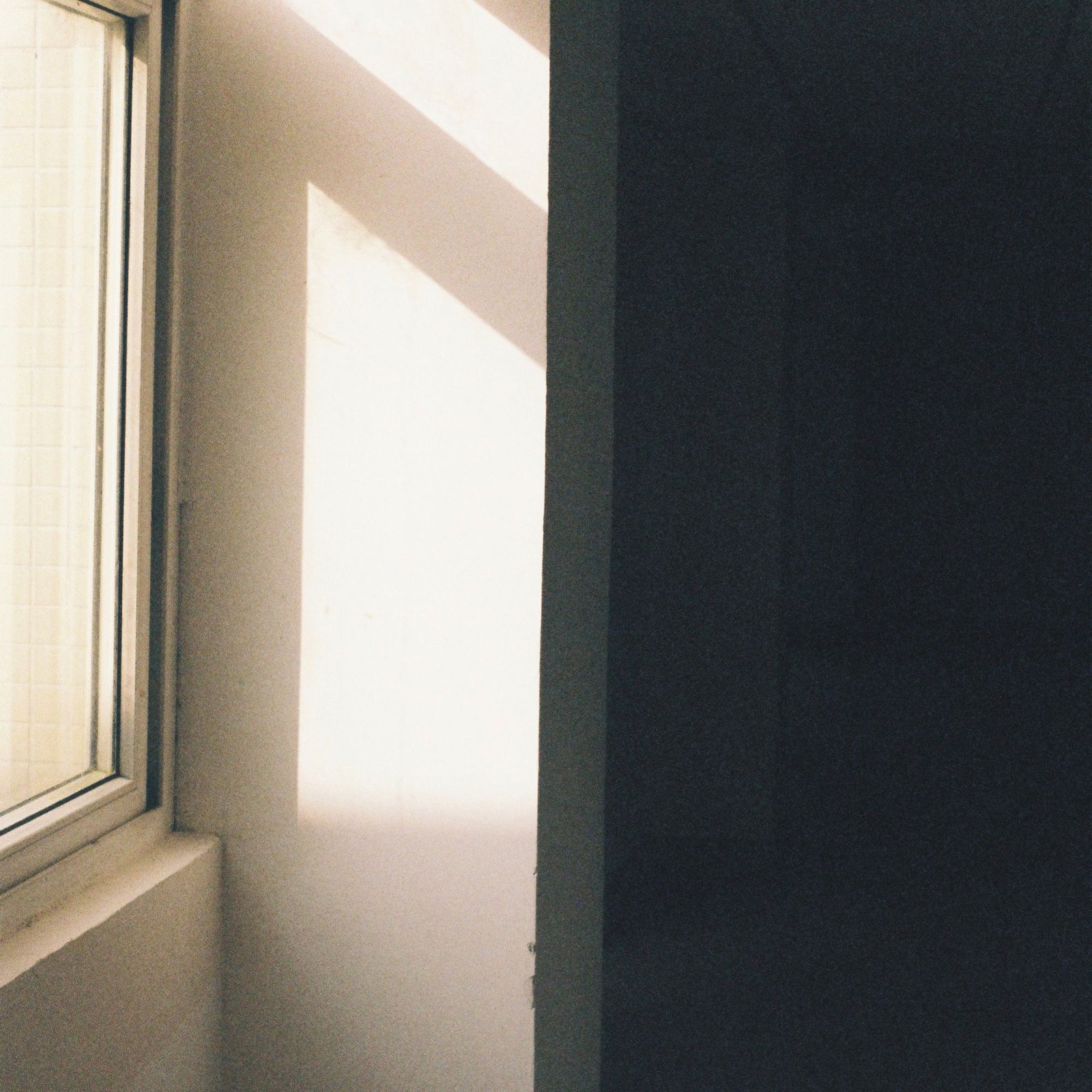 Sunlight falling across a dim concrete room from a high window