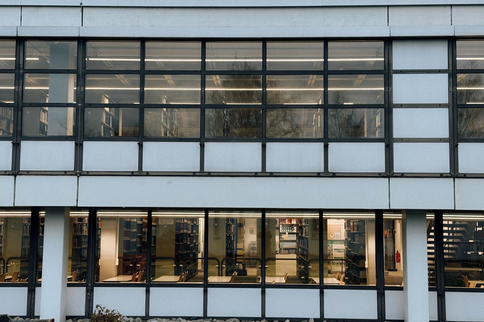 Long modernist glass building with slender mullions and a deep colonnade