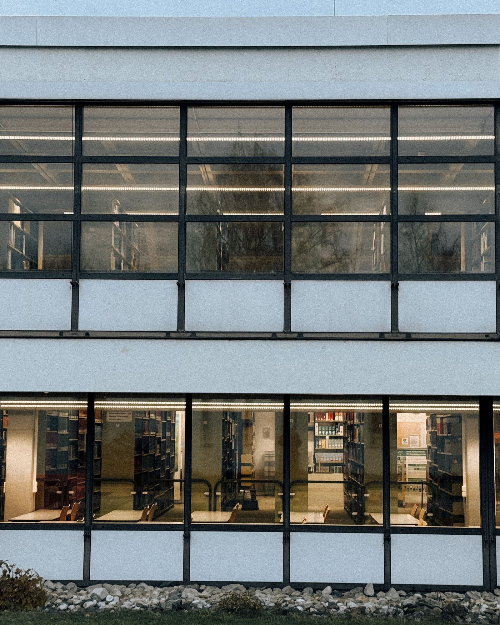 Long modernist glass building with slender mullions and a deep colonnade