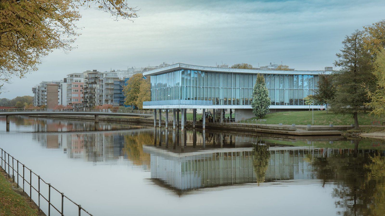 Long glass pavilion reflected in still water at dusk