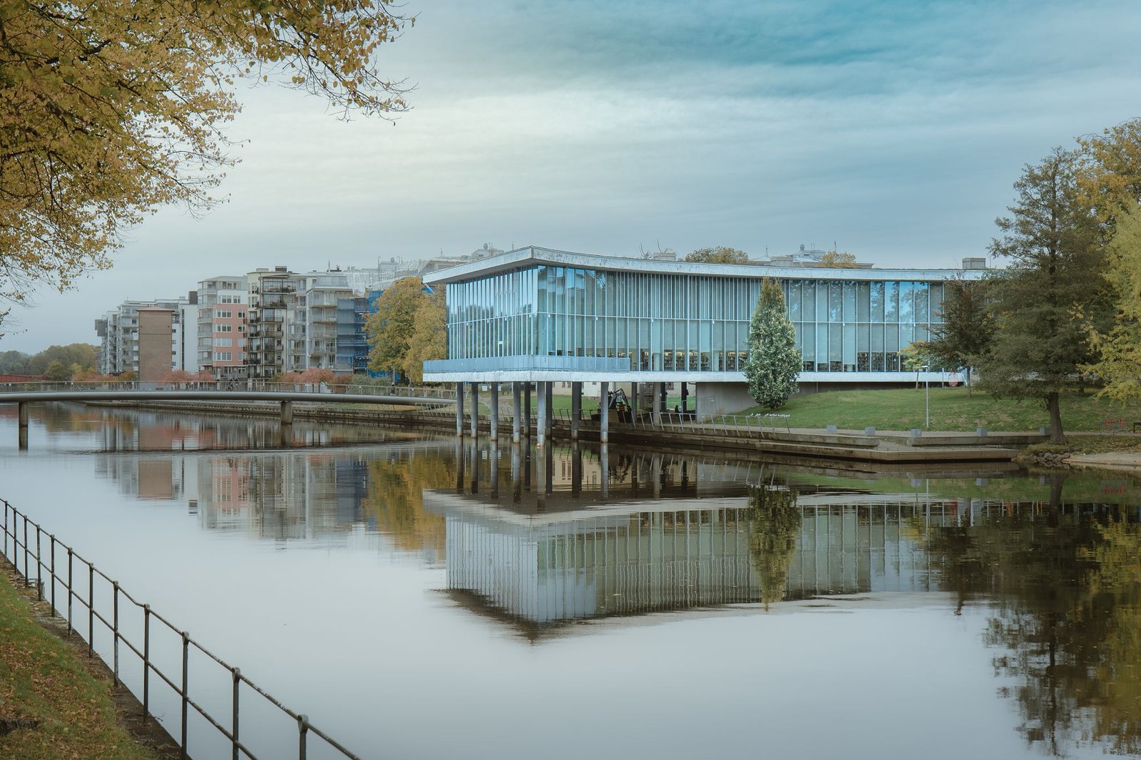 Long glass pavilion reflected in still water at dusk