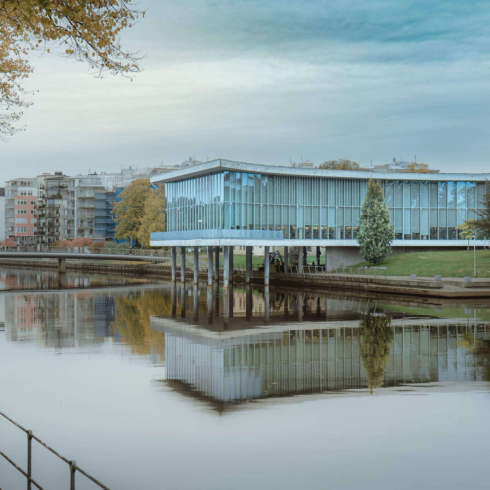Long glass pavilion reflected in still water at dusk