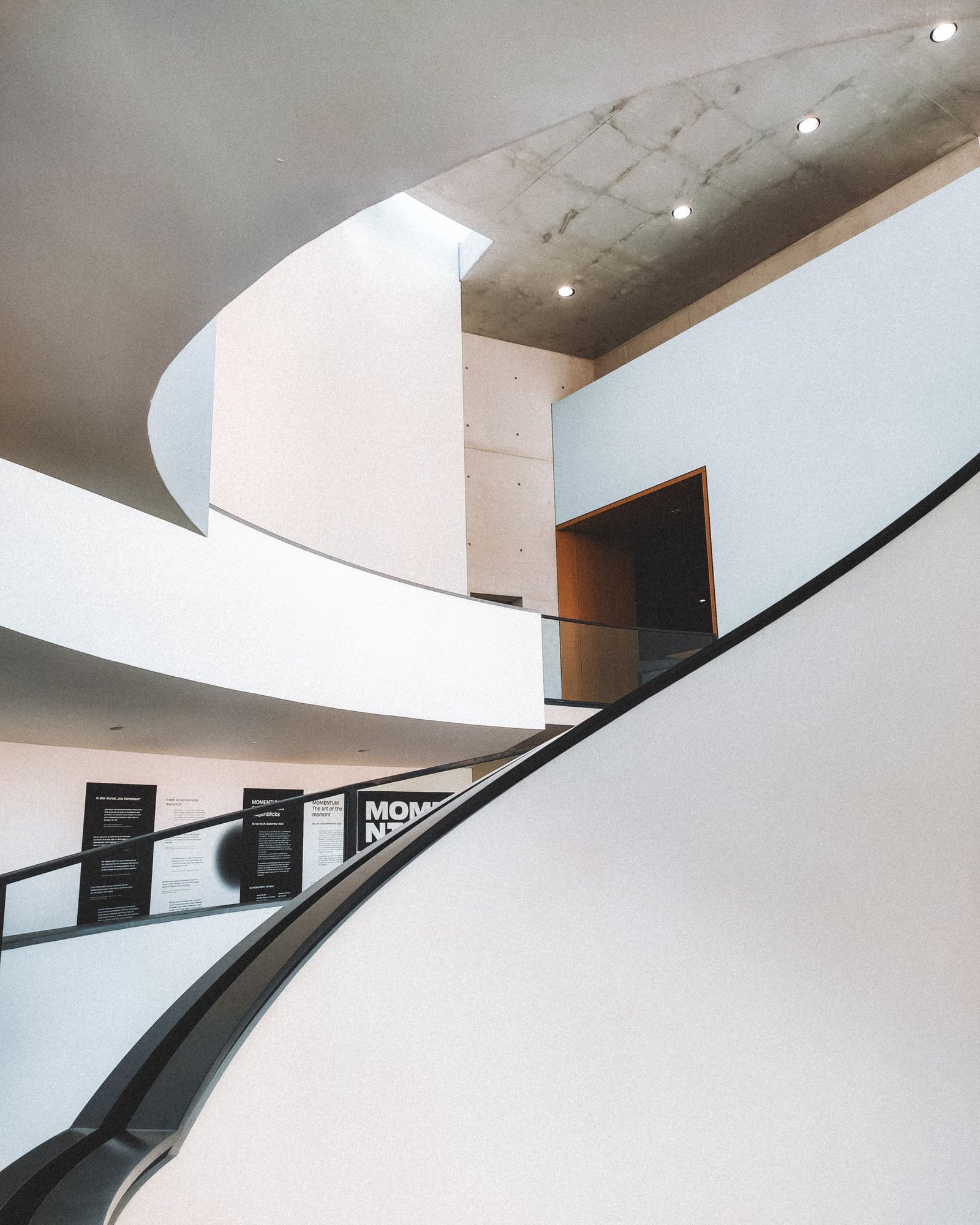 Sweeping white staircase curving through a double-height space