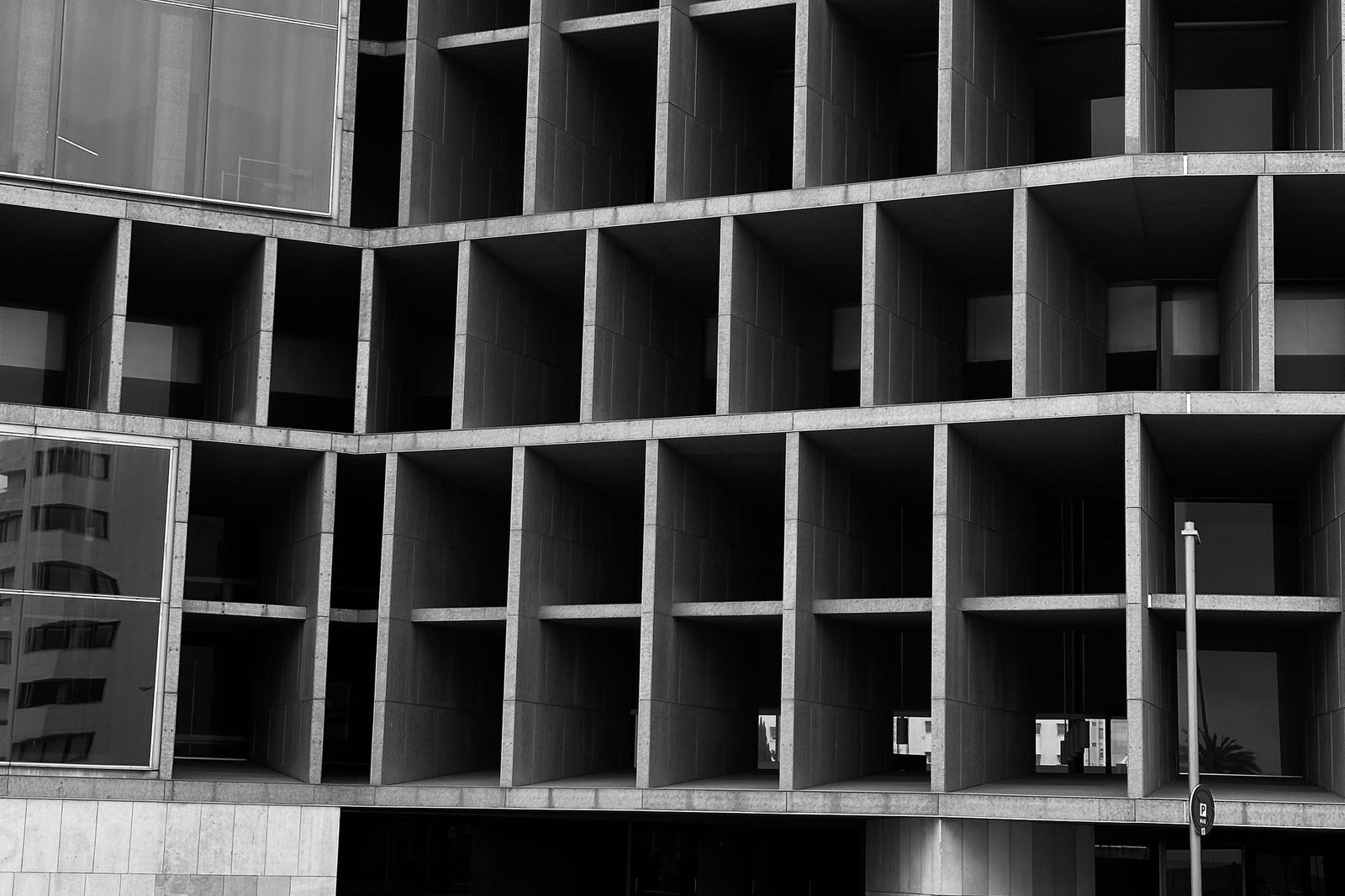 Deep concrete grid facade photographed in black and white against an overcast sky
