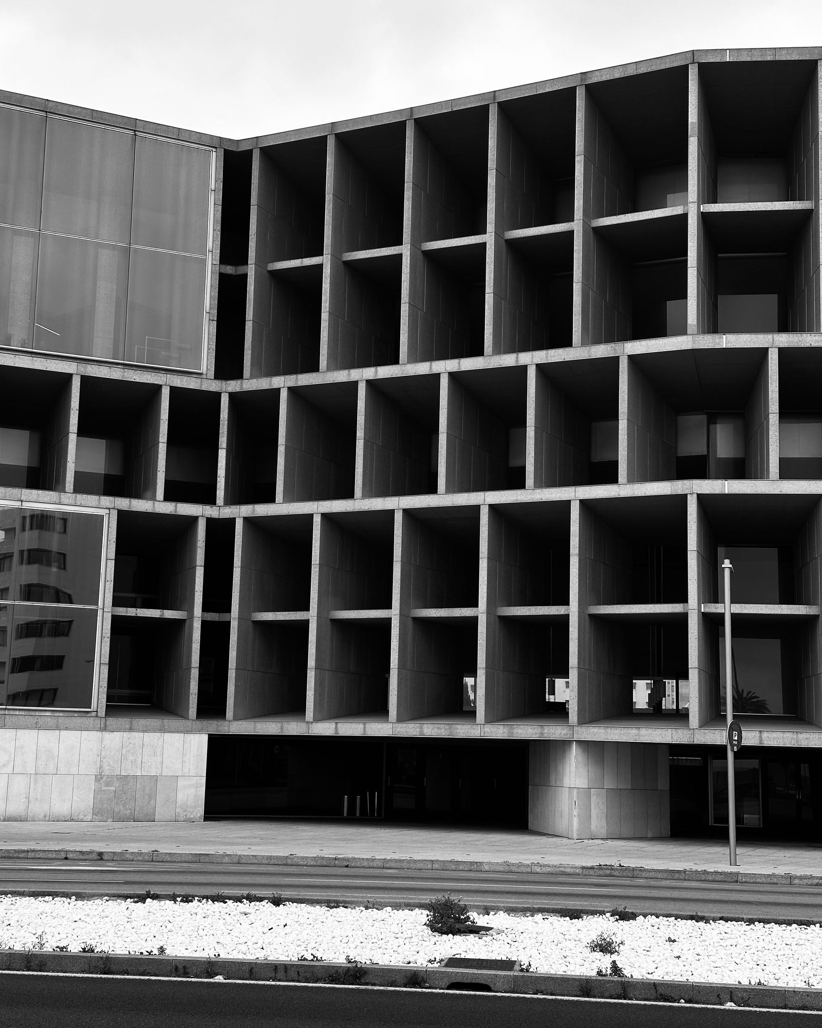 Deep concrete grid facade photographed in black and white against an overcast sky