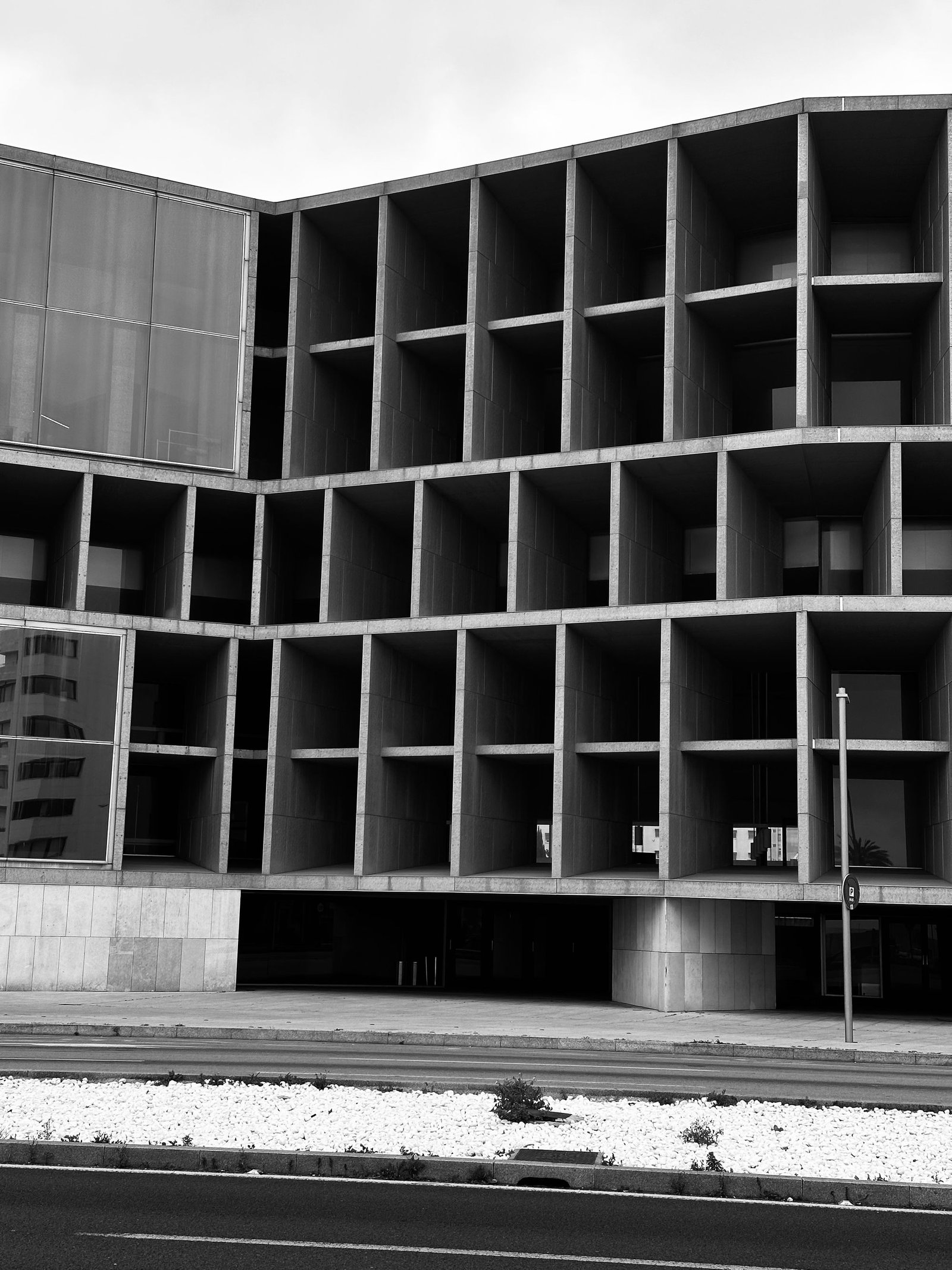 Deep concrete grid facade photographed in black and white against an overcast sky