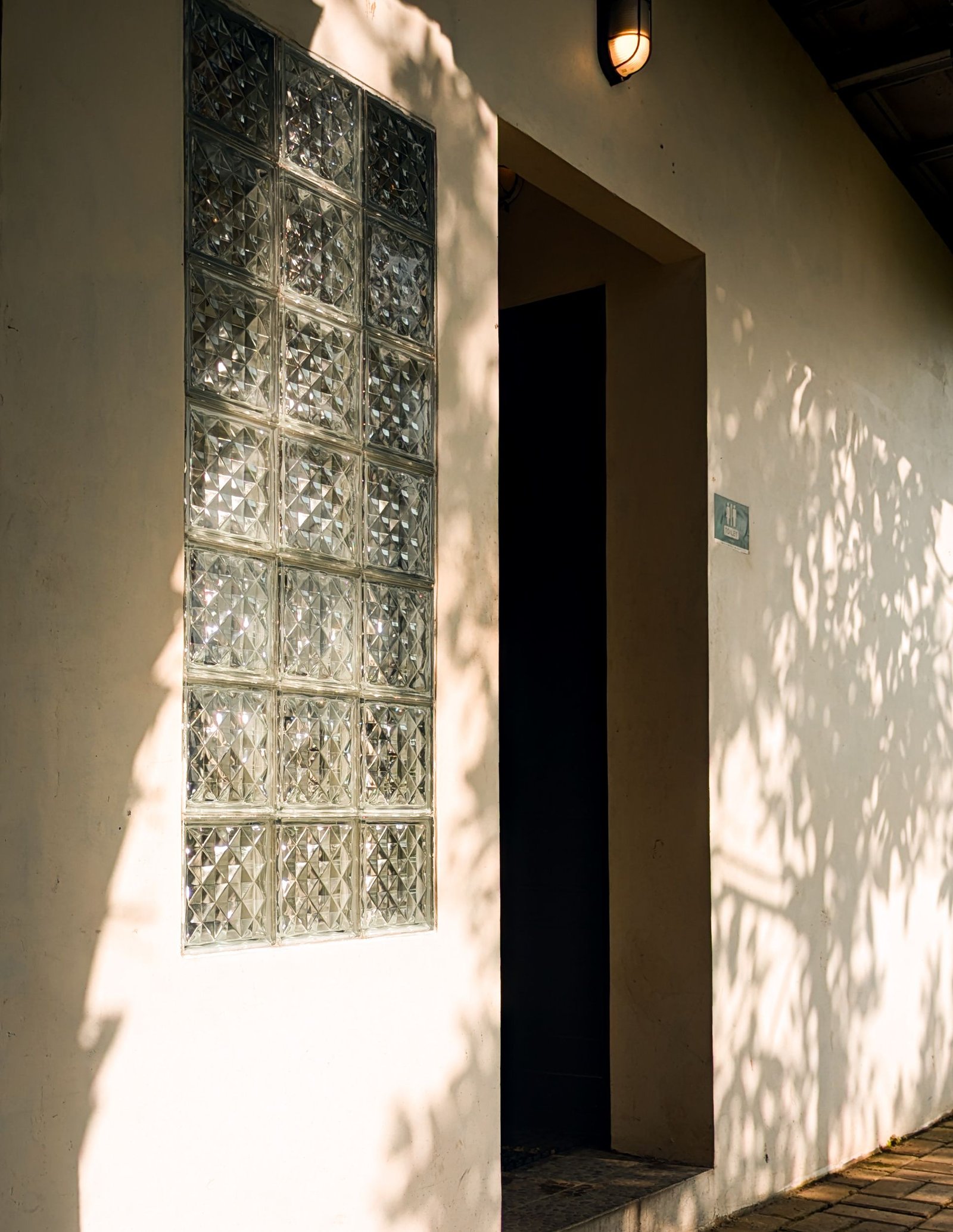 Sunlight through a screen falling on a lime-washed wall and hanging textile
