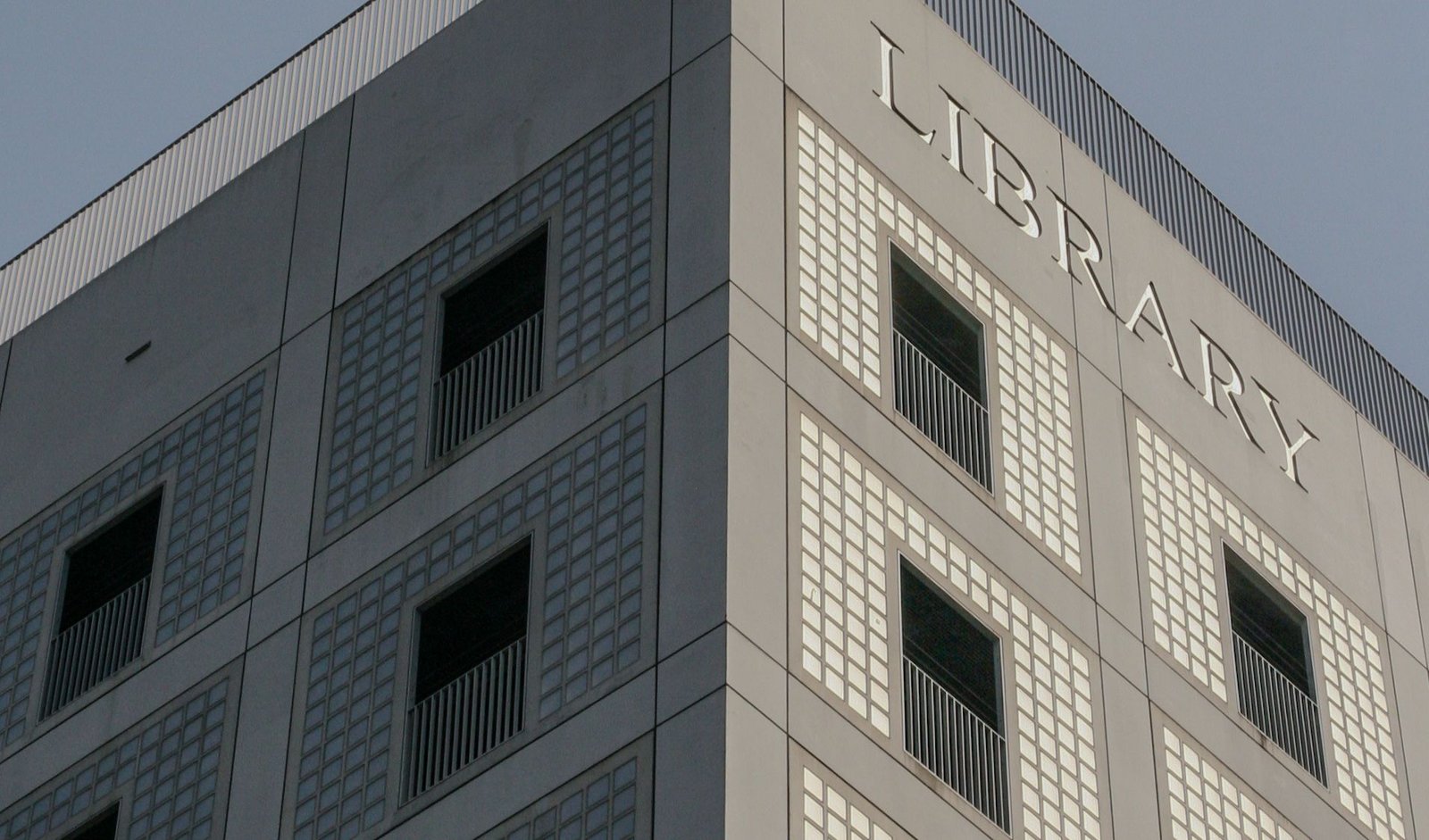 Corner of a pale gridded building standing against a clear sky