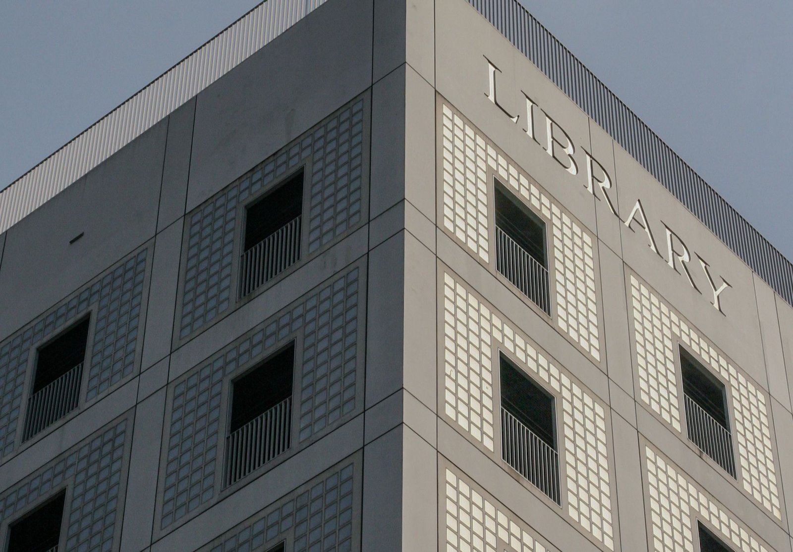 Corner of a pale gridded building standing against a clear sky