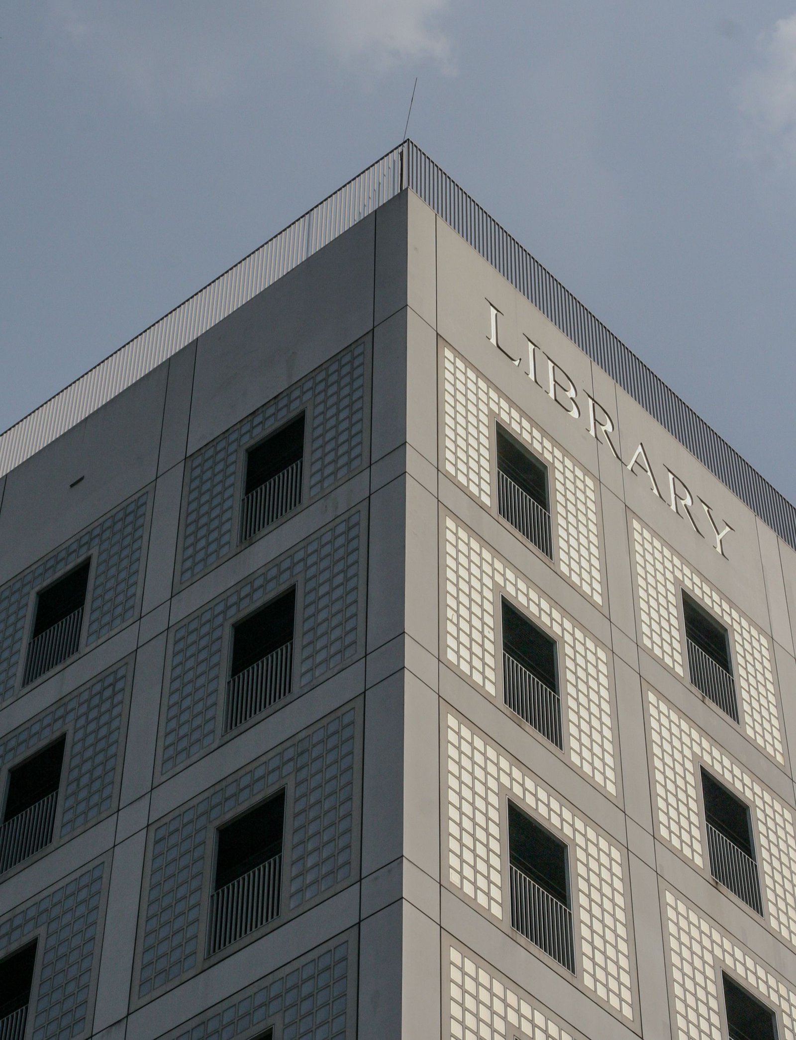 Corner of a pale gridded building against a clear sky