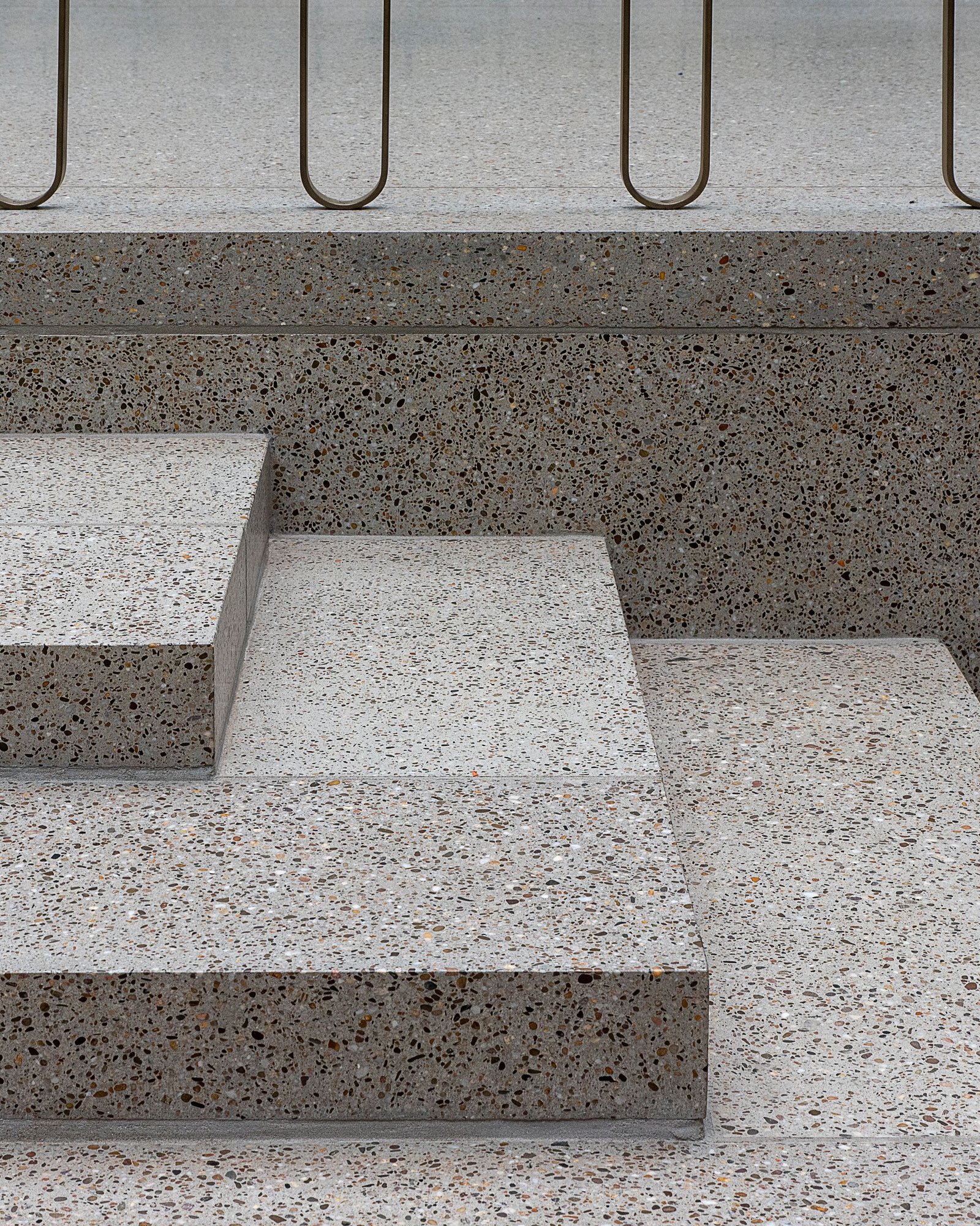 Terrazzo steps with a slender brass handrail