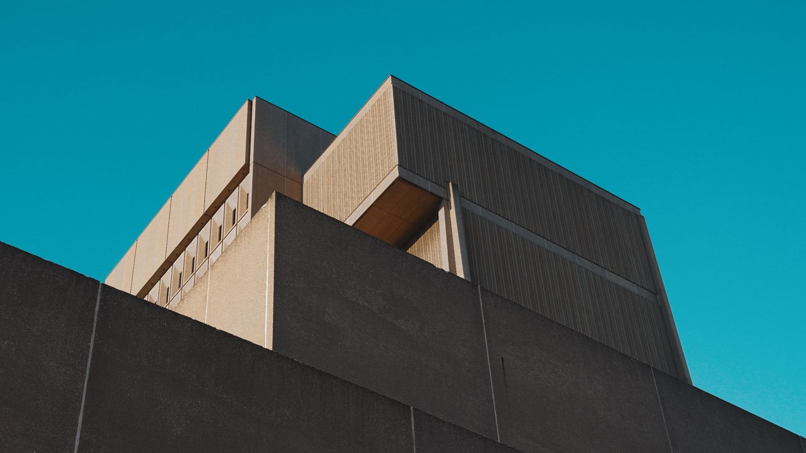 Angular concrete building mass photographed against a deep blue sky