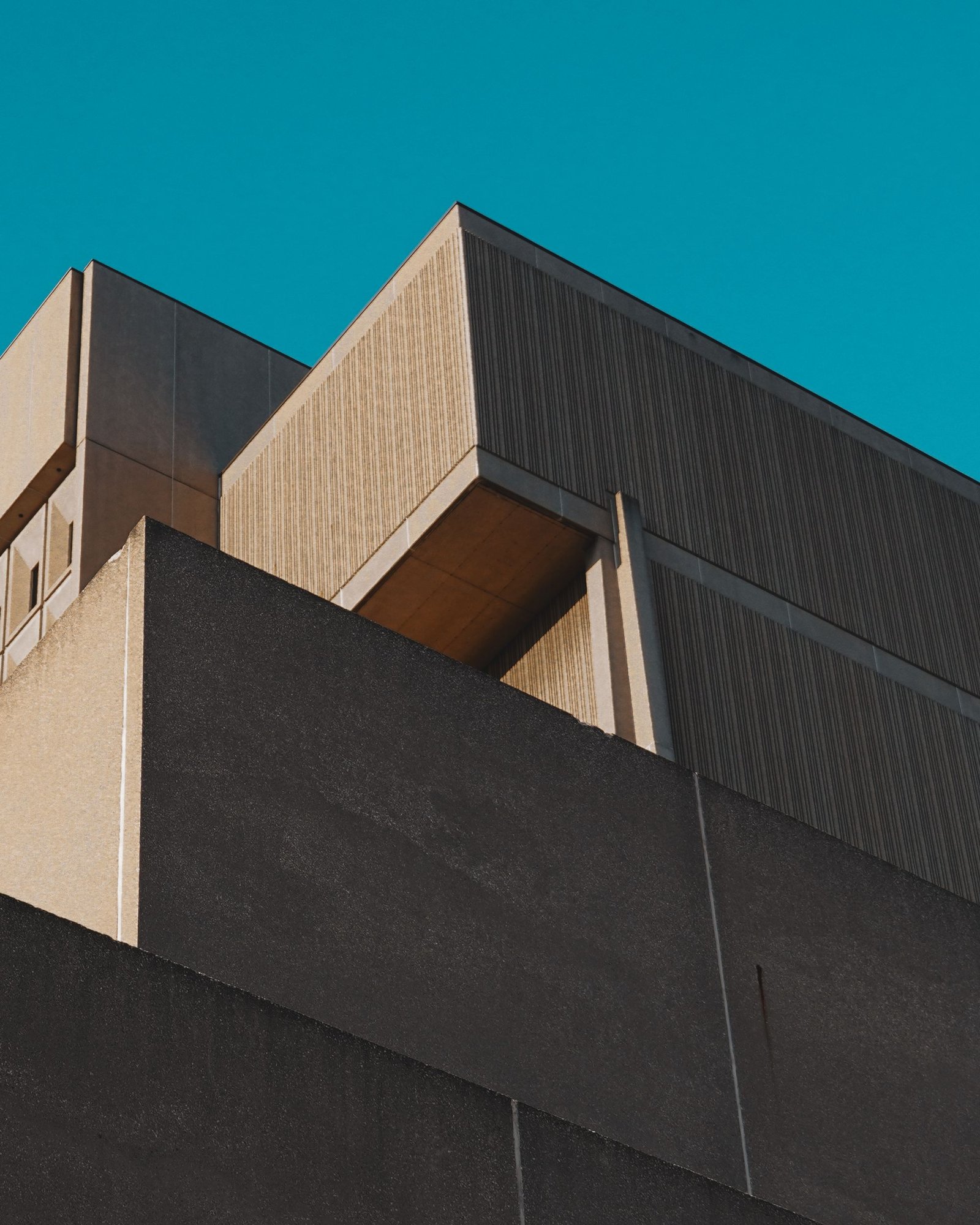 Angular concrete building mass photographed against a deep blue sky
