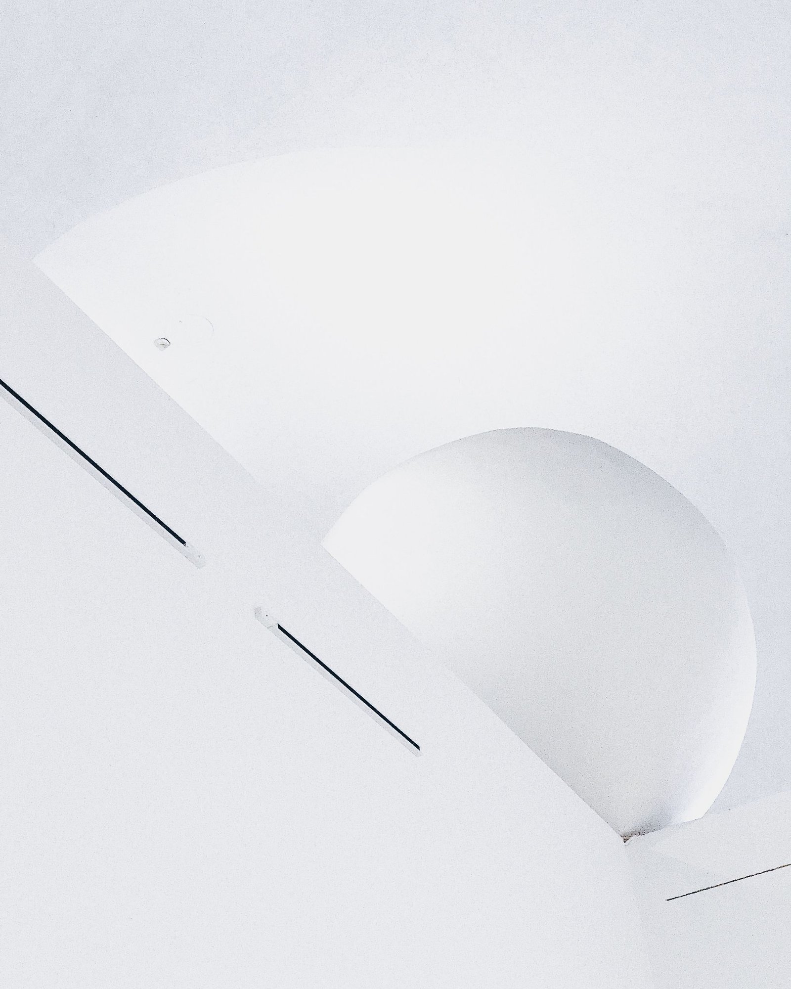 Curved white ceiling plane meeting a wall in soft daylight