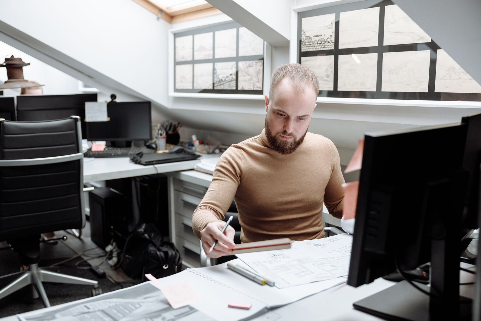 Architecture studio with rooflights, long desks, drawings pinned to the walls