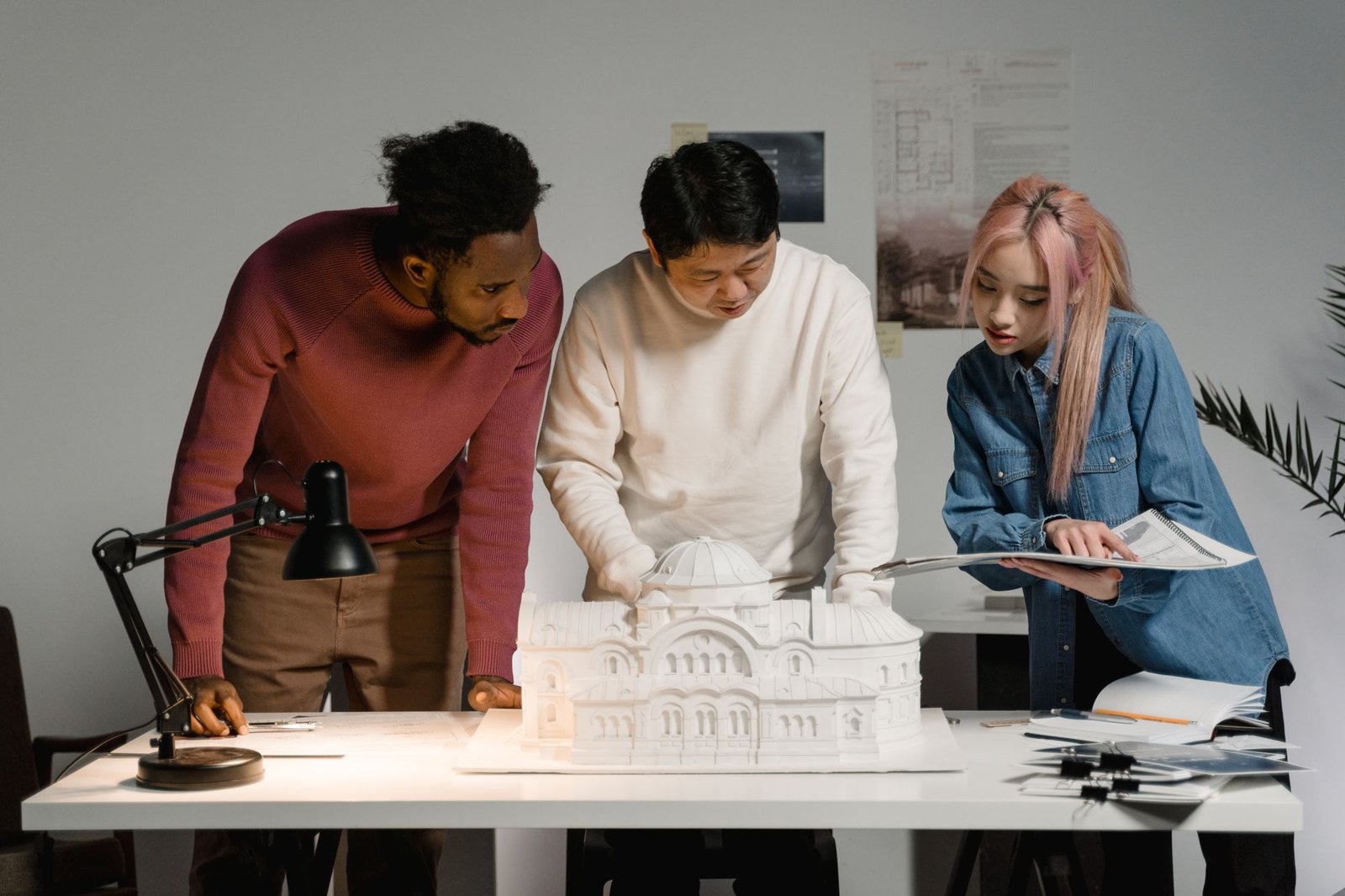 Three colleagues gathered around a white architectural model on a studio table