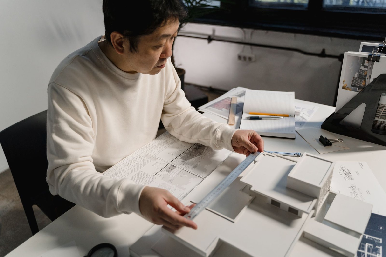 Person examining a large architectural model with a measuring tool