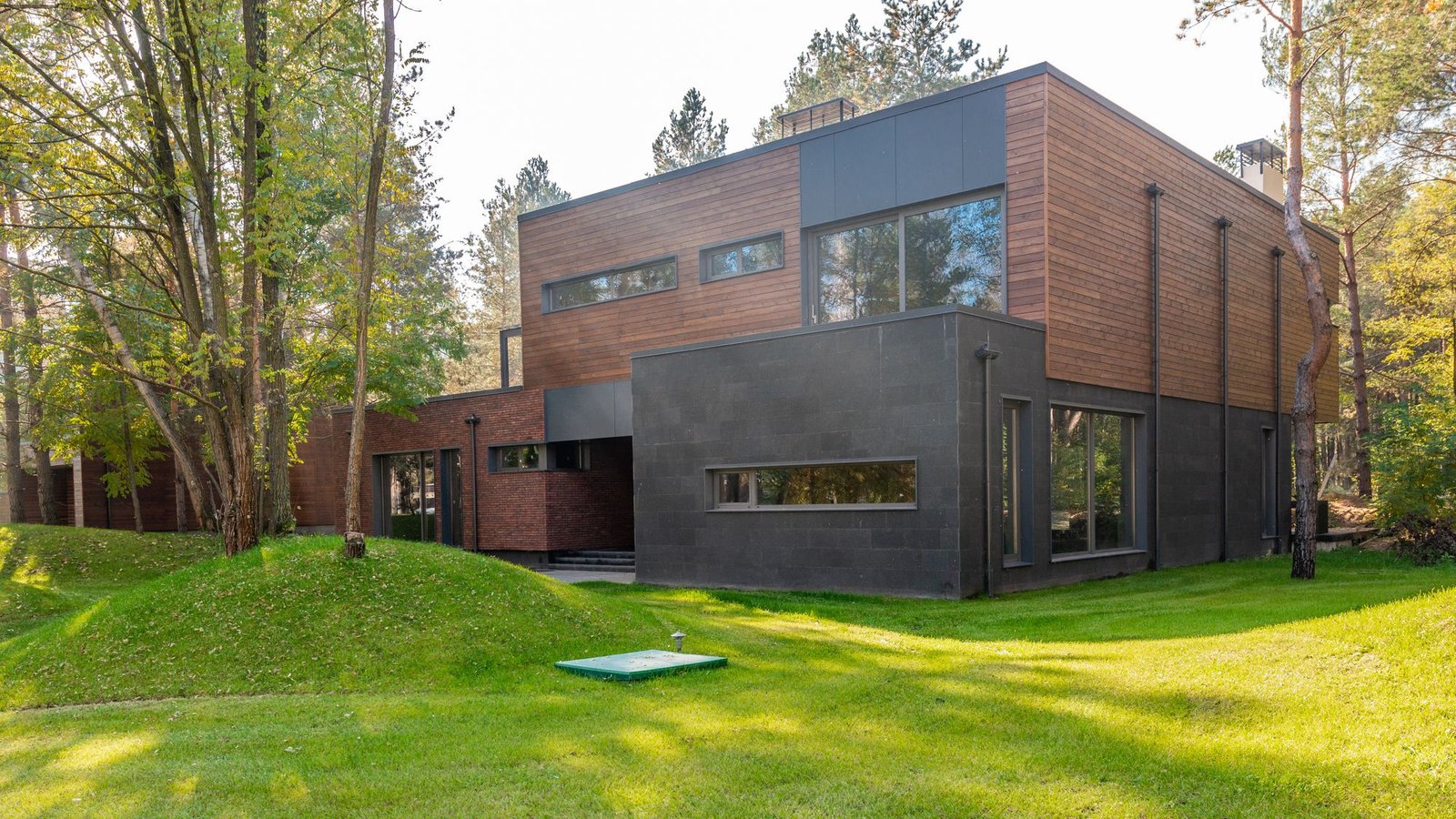Low dark timber house on a clearing of cut grass
