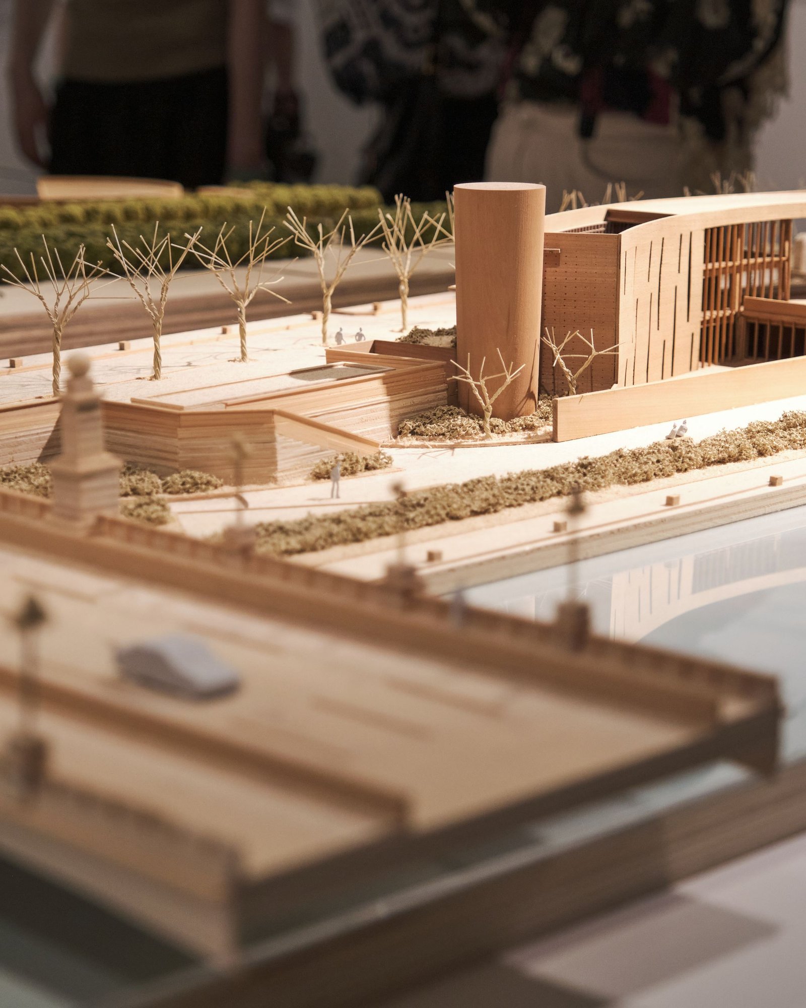 Timber and card site model showing a building set into a landscape with water