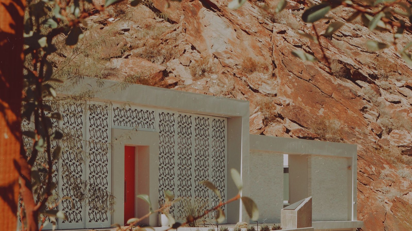Low concrete building settled into a rocky landscape under a pale sky