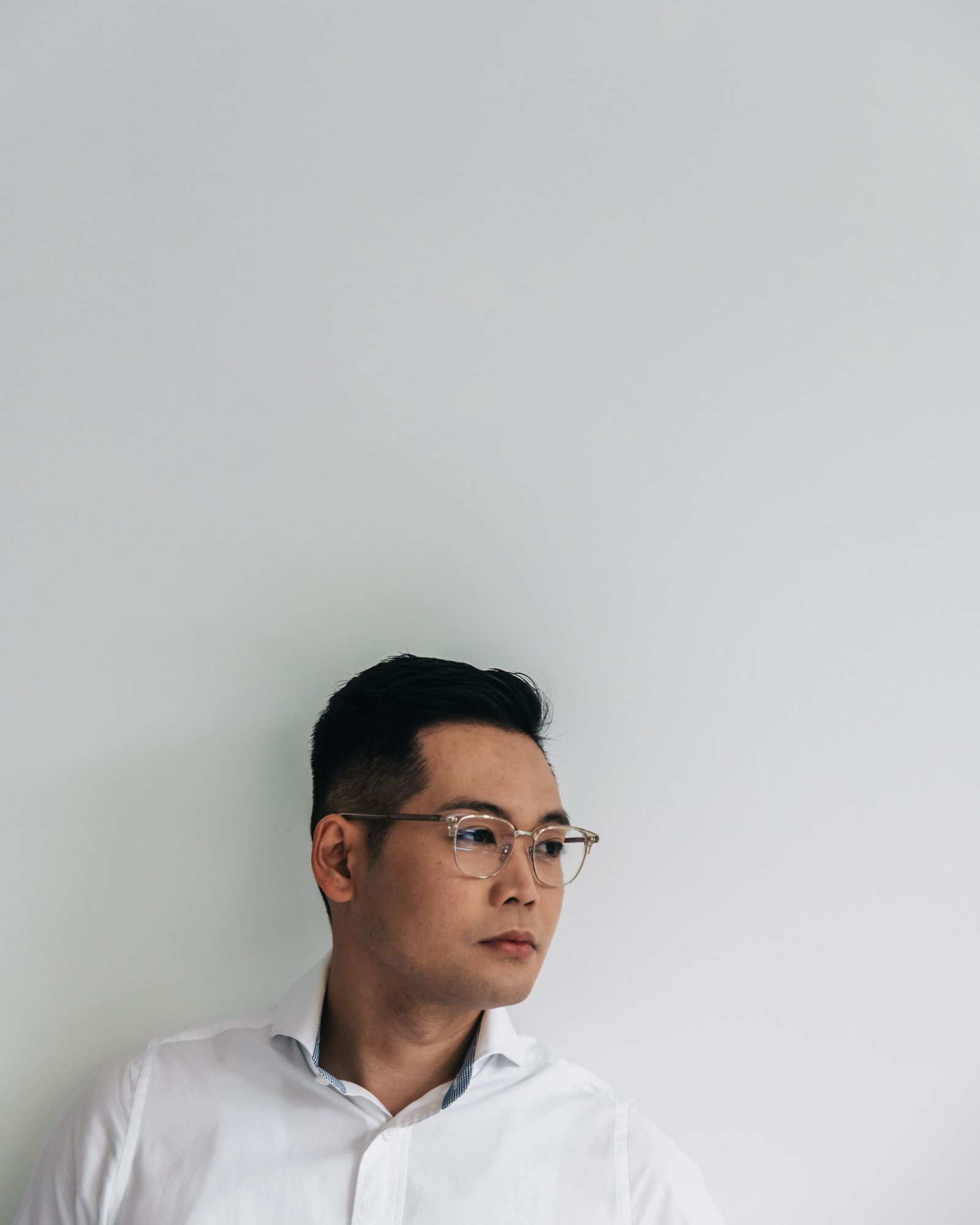 Portrait of a man wearing glasses and a white shirt against a pale background