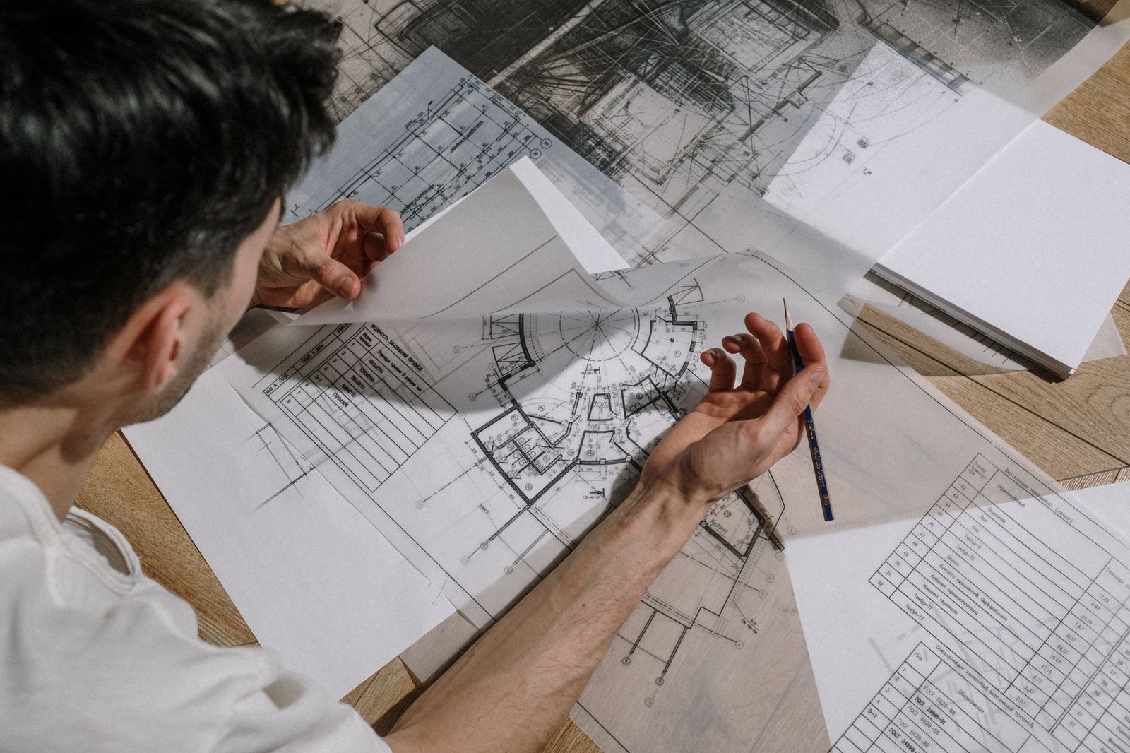 Architect leaning over drawings and sketches spread across a large desk