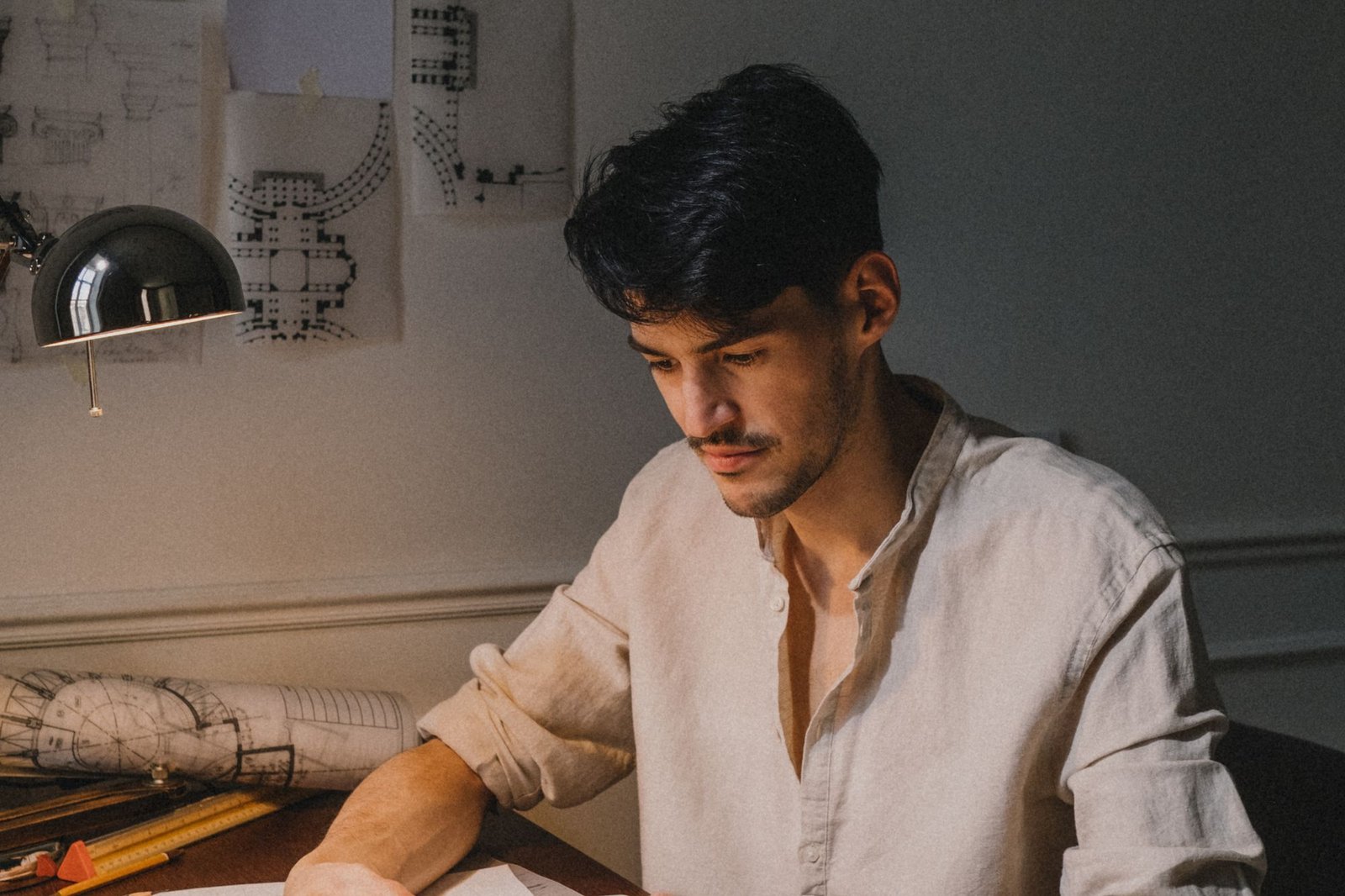 Architect working at a desk with drawings and a scale model under a lamp