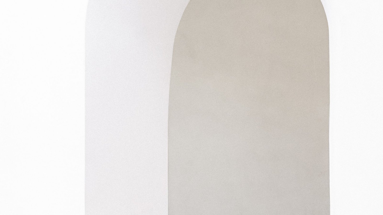 Arched white doorway cut through a thick plaster wall