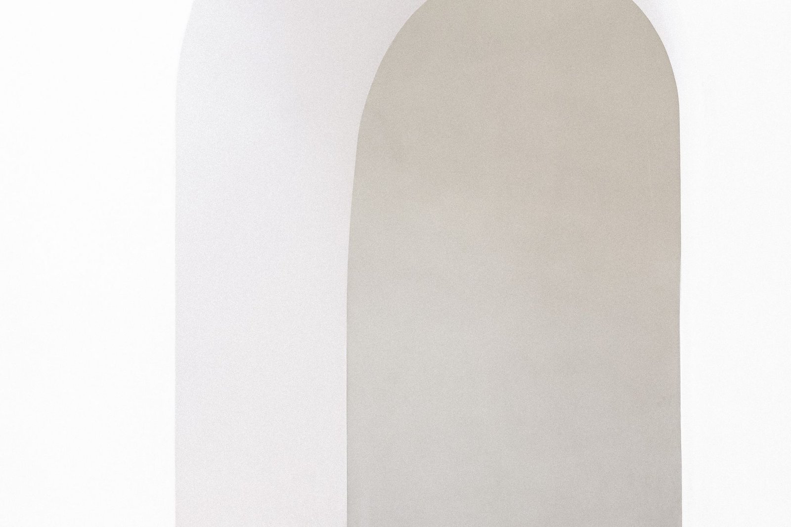 Arched white doorway cut through a thick plaster wall