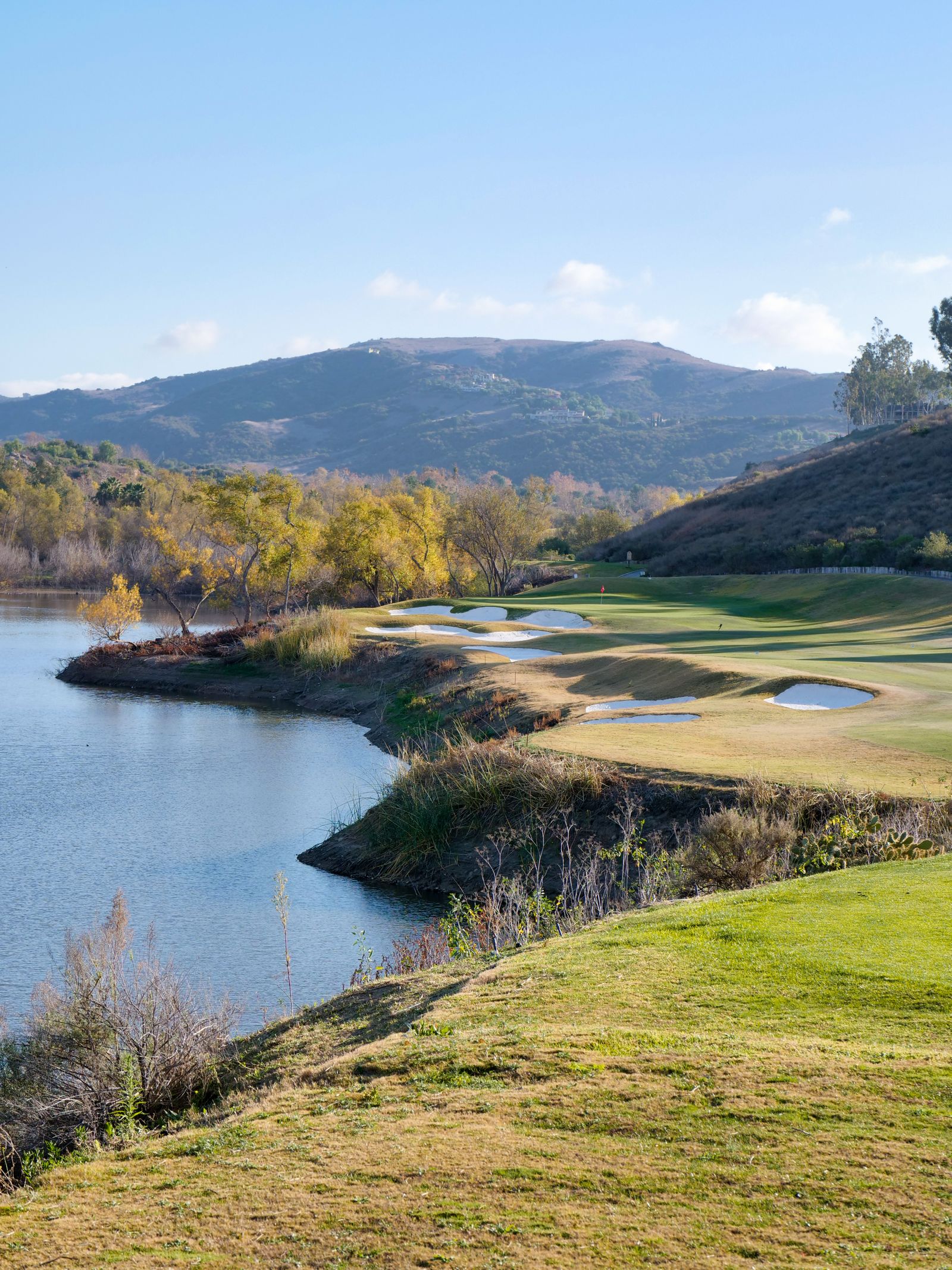 A mountain golf hole set beside a still lake