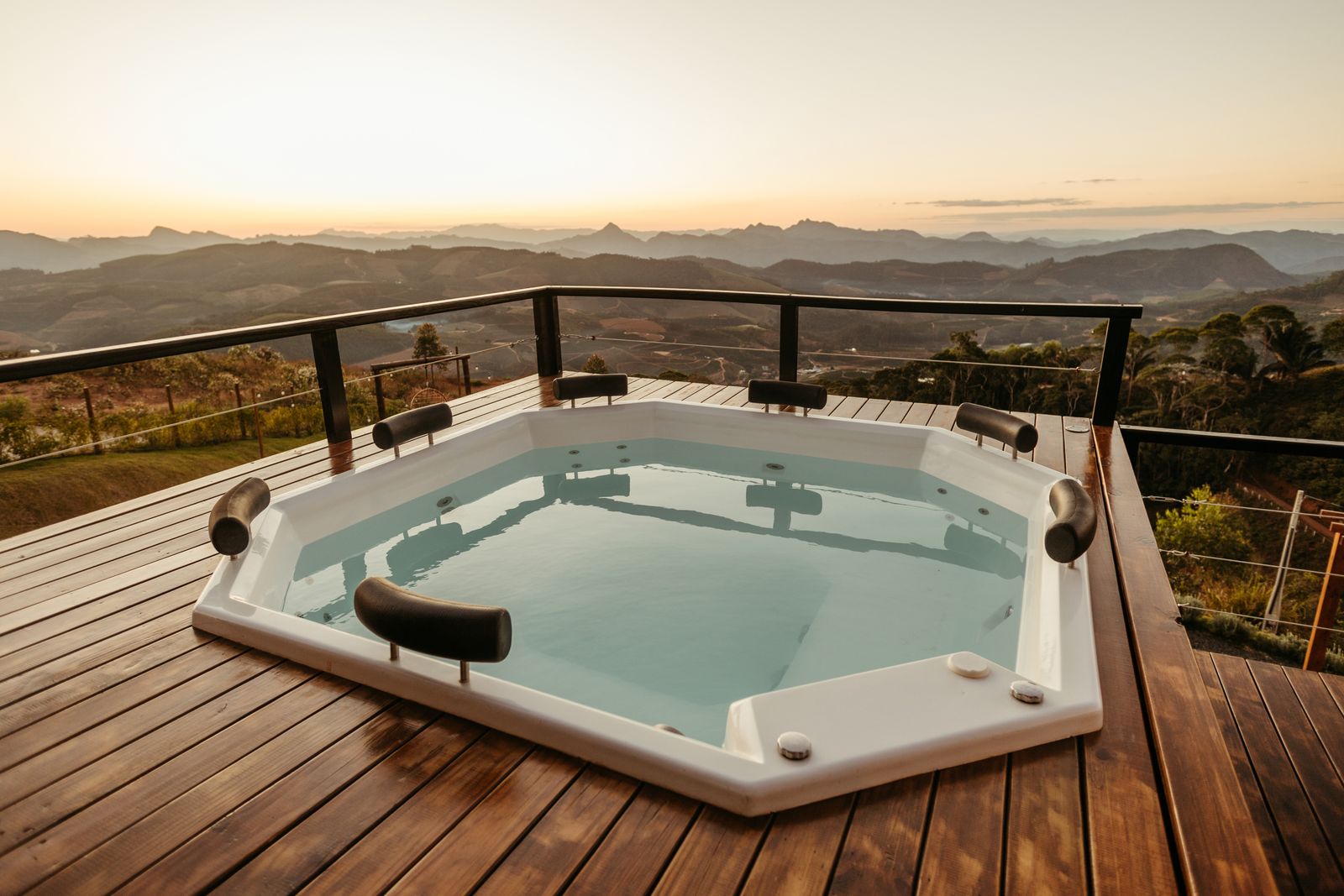A hot tub on a deck with a sweeping mountain view at sunset