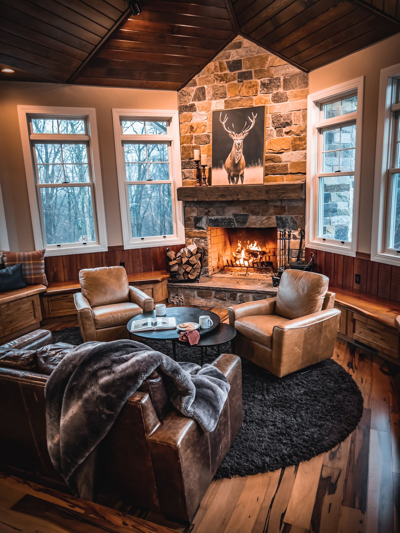 A warm lodge living room with a fireplace and leather chairs