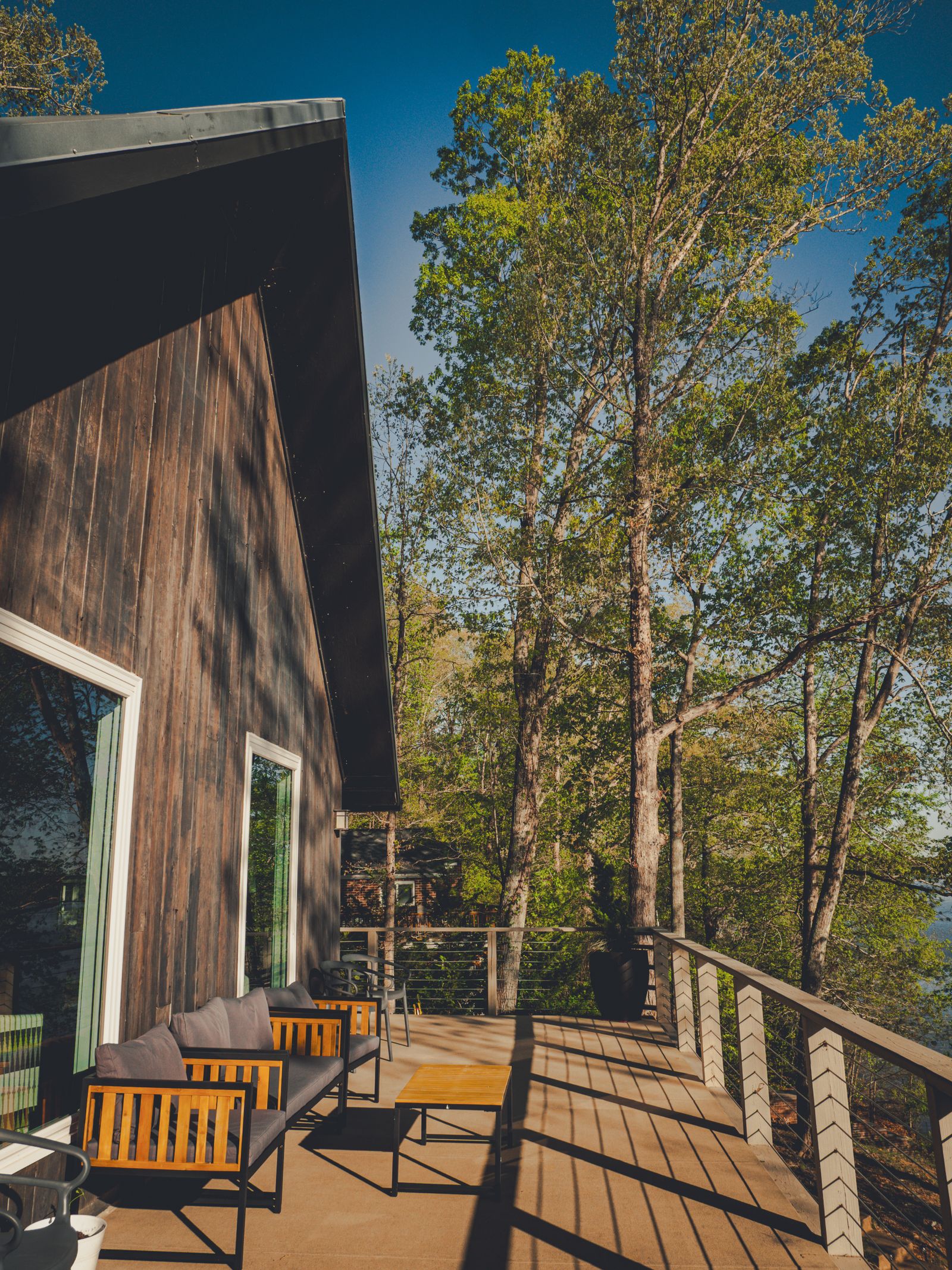 A modern residence with a sunlit deck cantilevered over lush forest